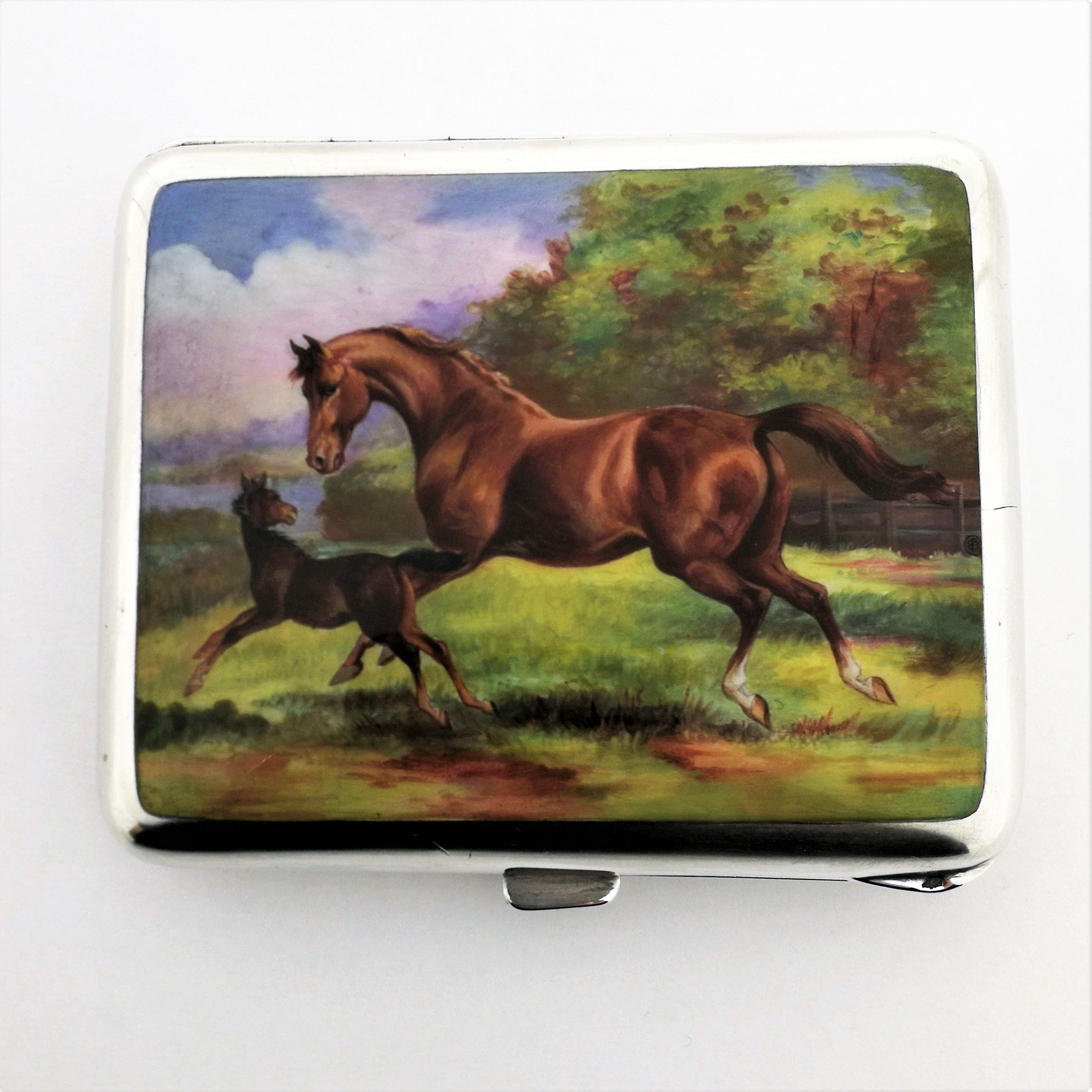 A gorgeous antique Austrian silver & enamel cigarette case. The case features a magnificent enamel scene on the front cover showing a mare and her colt cantering through the country side. The horses and landscape are created in rich, vibrant colors