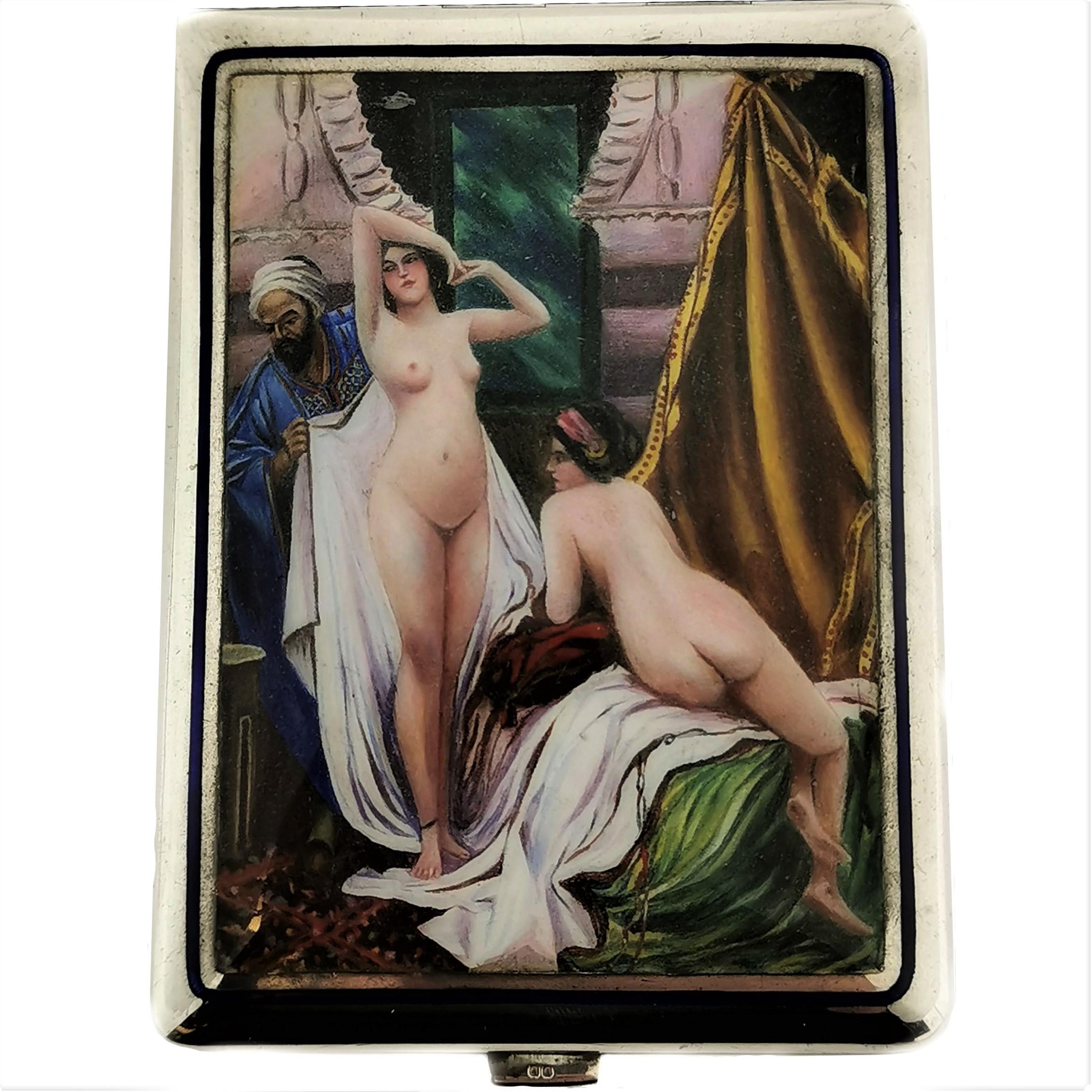 A magnificent Antique Silver Cigarette Case featuring a detailed enamel scene on the front cover rendered in rich colour and vivid detail. The scene shows two nude women lounging on luxurious fabrics as a man hands them a towel. The back of the Case