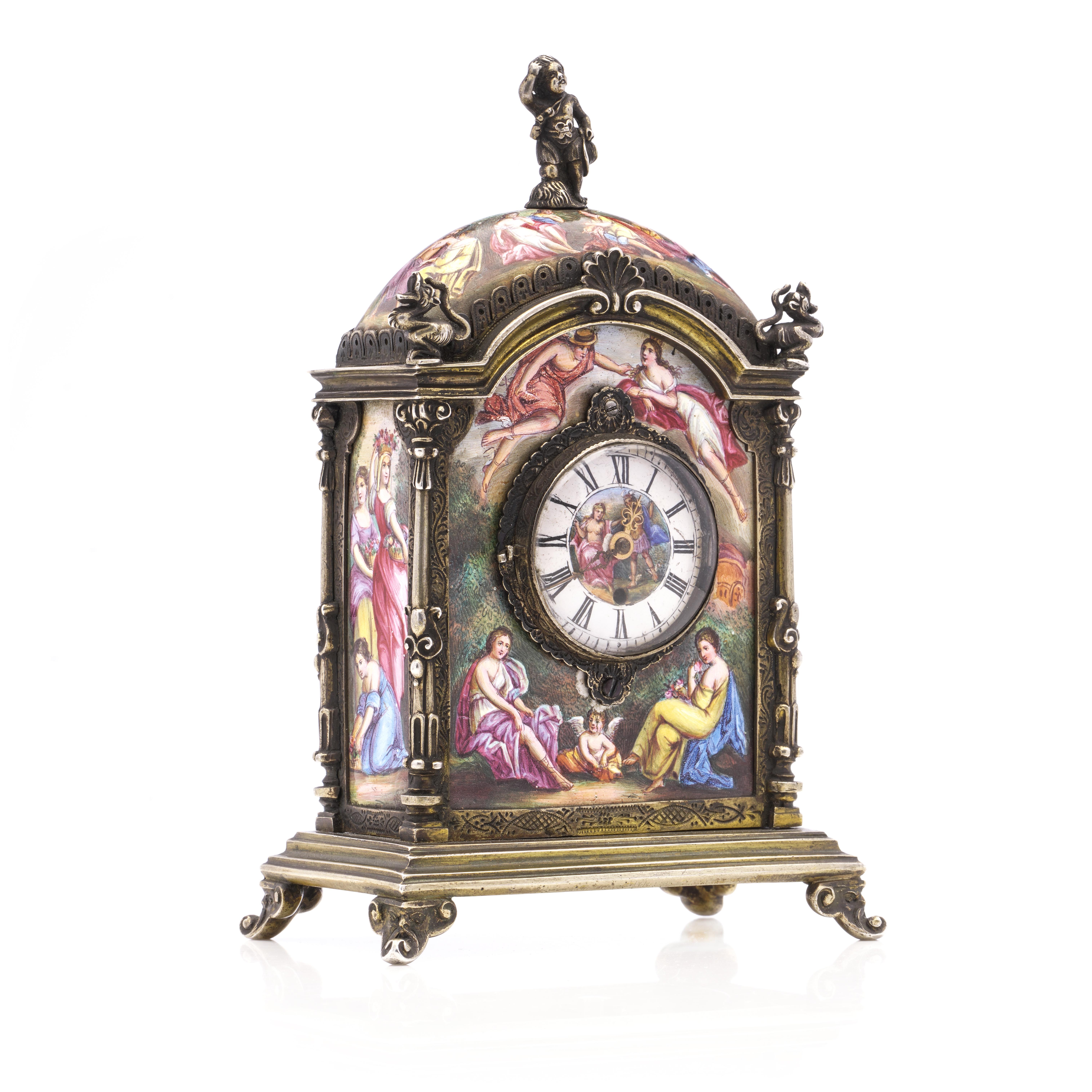 This is an antique Austrian silver gilt and enamel clock with an arched rectangular form on a stepped base, featuring scroll bracket feet. The corners of the clock are formed as pilasters surmounted by mythical creatures. There is a figure of a boy