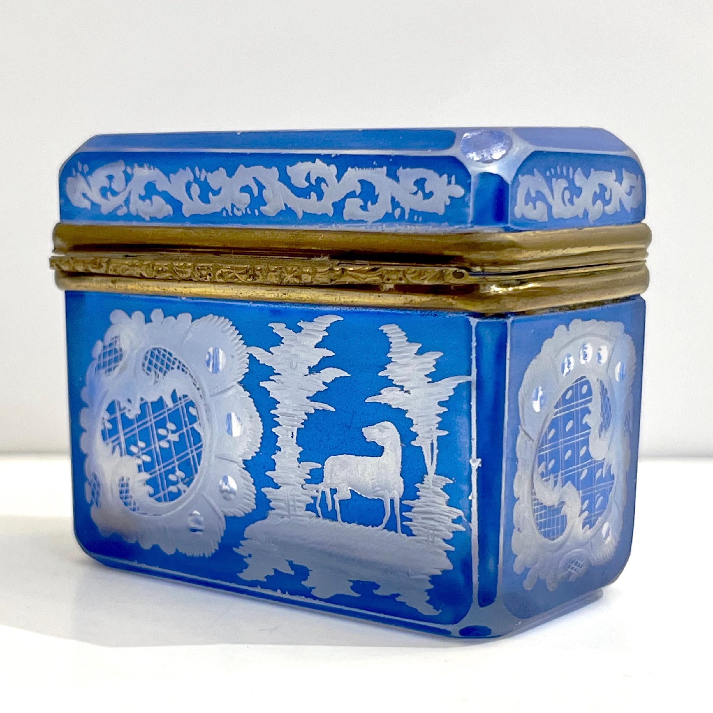 Cet ancien coffret à anneaux est un petit bijou du XIXe siècle en cristal de Bohème d'une heureuse couleur azur céruléen, entièrement taillé et gravé à la main, recouvert de cristal clair, Œuvre d'Art pour l'étendue du décor habile sur de si petites