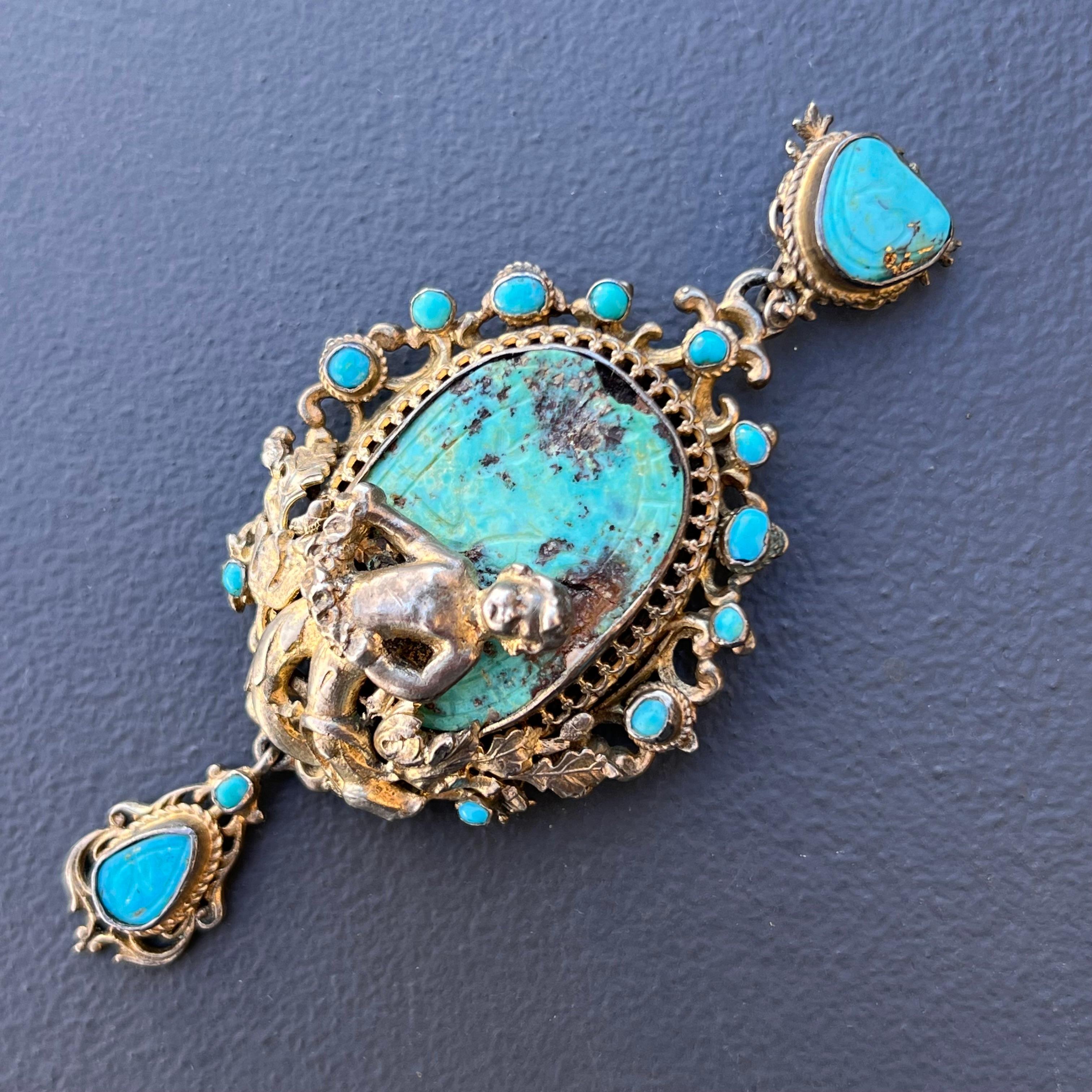 Antique gold gilded silver renaissance revival Austro Hungarian pendant featuring a large central bezel set turquoise cabs set on an closed back setting and an Angel Cherub holding flower on top and ornate bezel set turquoise boarder. Back is also