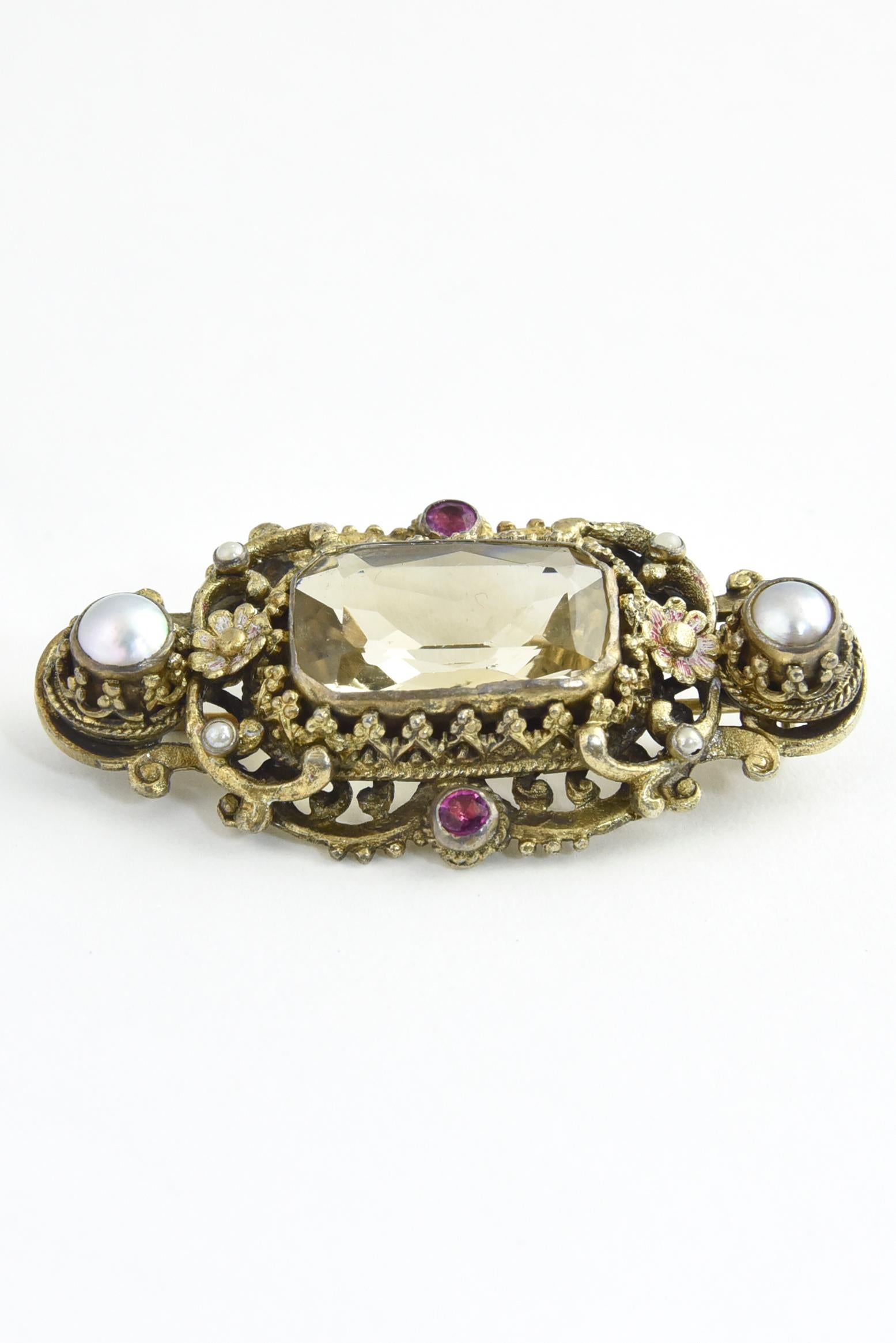 Created between 1860 and 1910 in work shops in Austria-Hungary, this gold gilded 800 silver brooch features a rectangular faceted citrine. The central gem is surrounded by button pearls and pink tourmaline with floral details.