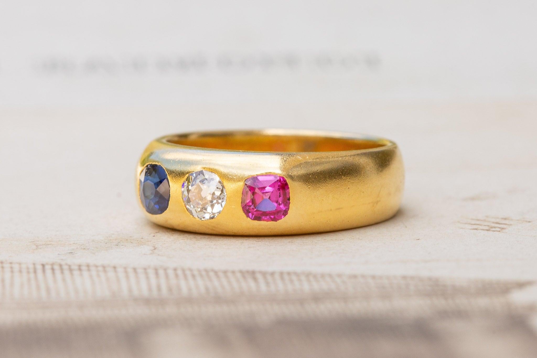 A stunning antique gold ring, made in Vienna circa 1910. This three-stone gypsy ring is set with a sapphire, an old cut diamond, and a ruby - horizontally aligned in a French flag formation. Each of the gemstones are of very high quality, with