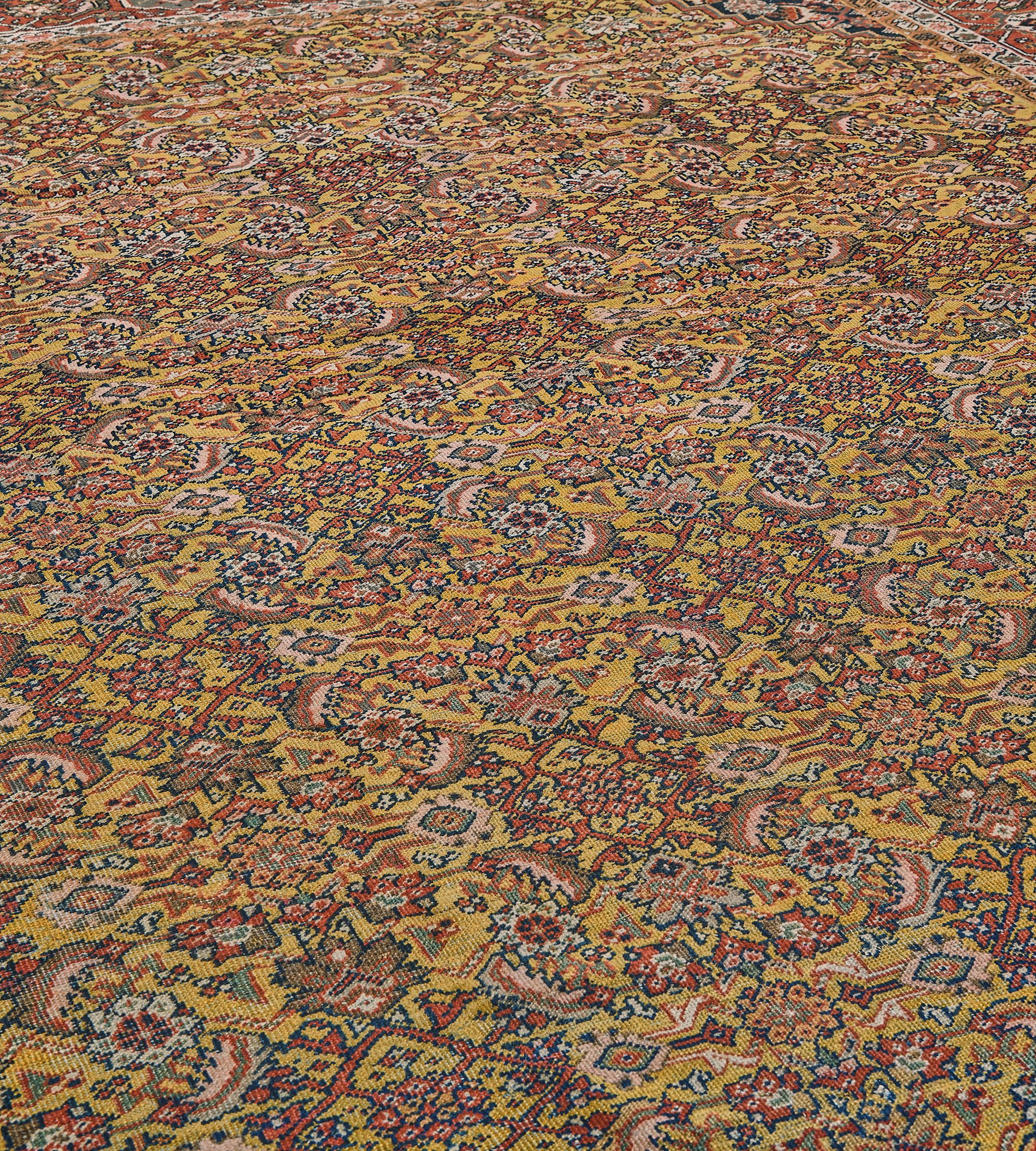 Dieser traditionelle, handgewebte persische Fereghan-Teppich hat ein goldenes Safran-Herati-Feld mit wechselseitig abgestuften indigoblauen Herati-Zwickeln in einer rubinroten Bordüre aus zarten, geschnürten Schildkrötenpalmetten zwischen
