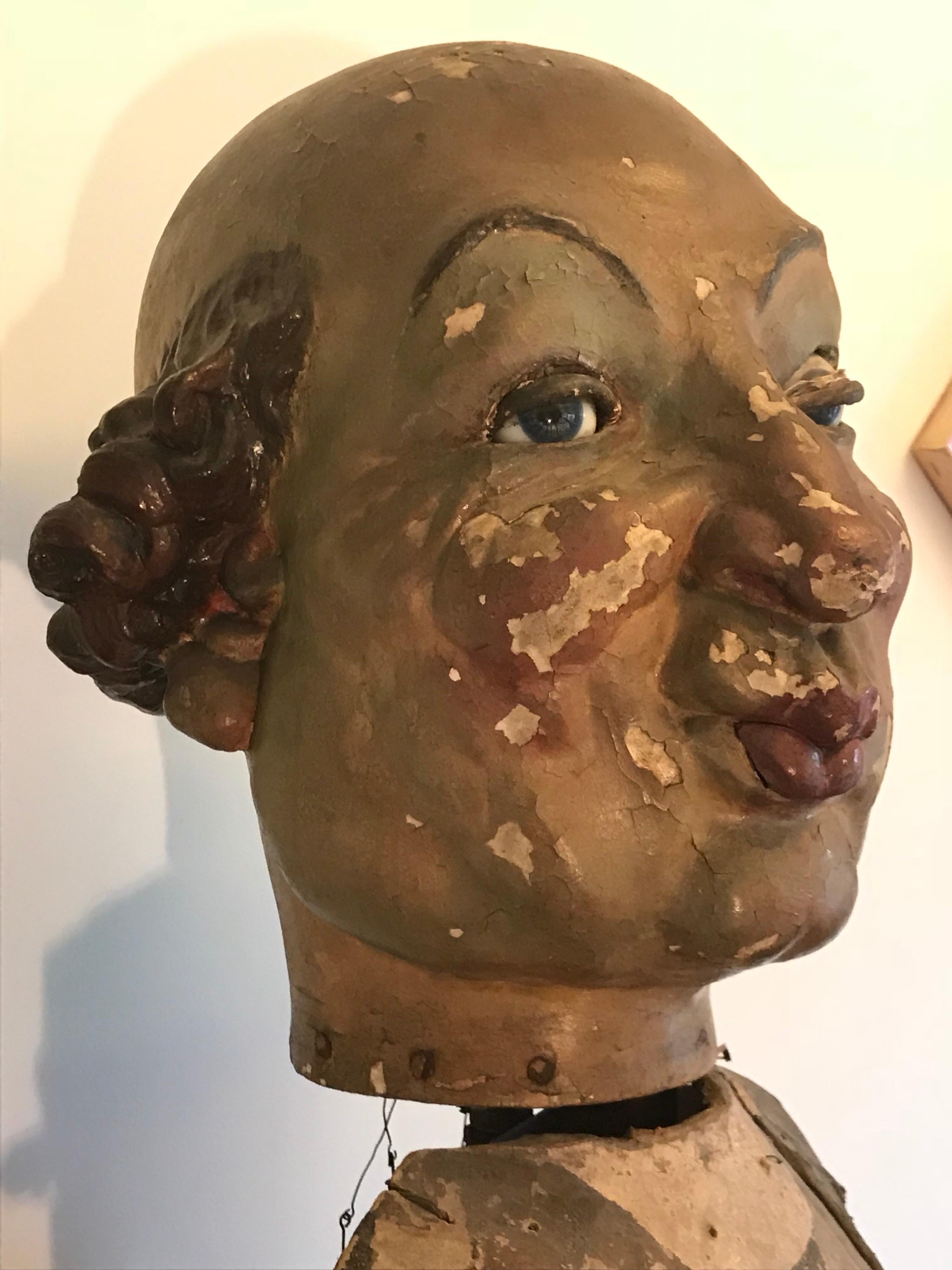 A fun piece. 
It's in the original condition showing ware and tare with patina and missing parts.
Nevertheless, it's great as a decorative art object.
The head is made of painted plaster with glass eyes, iron and wood with metal hardware with