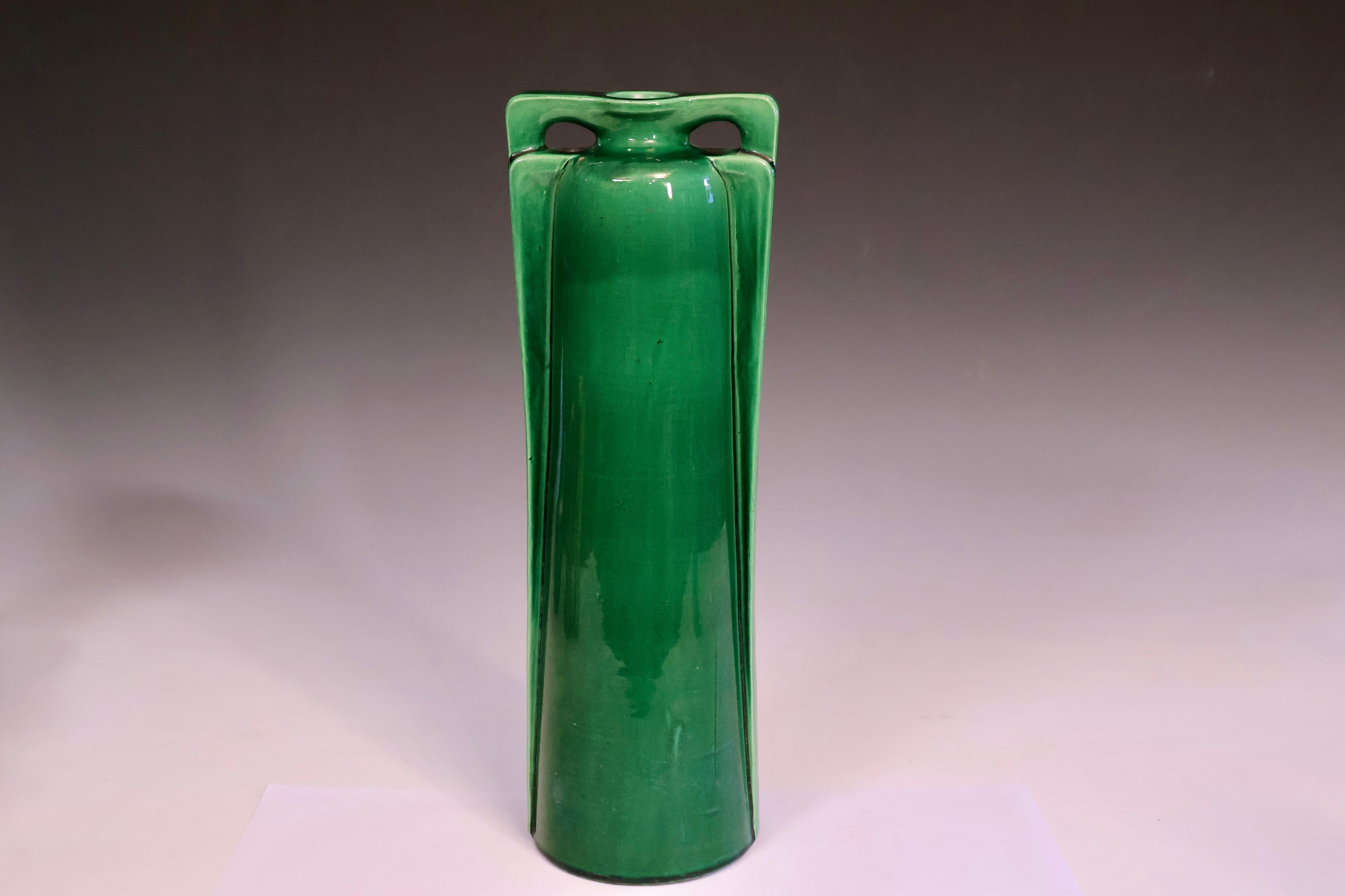 Antique Awaji pottery tall vase in deep green glaze. Hand turned. Circa 1920. The vase is tall and cylindrical, with a distinctive double buttress handle design at the neck, where each handle forms an elegant arch extending from the rim to the