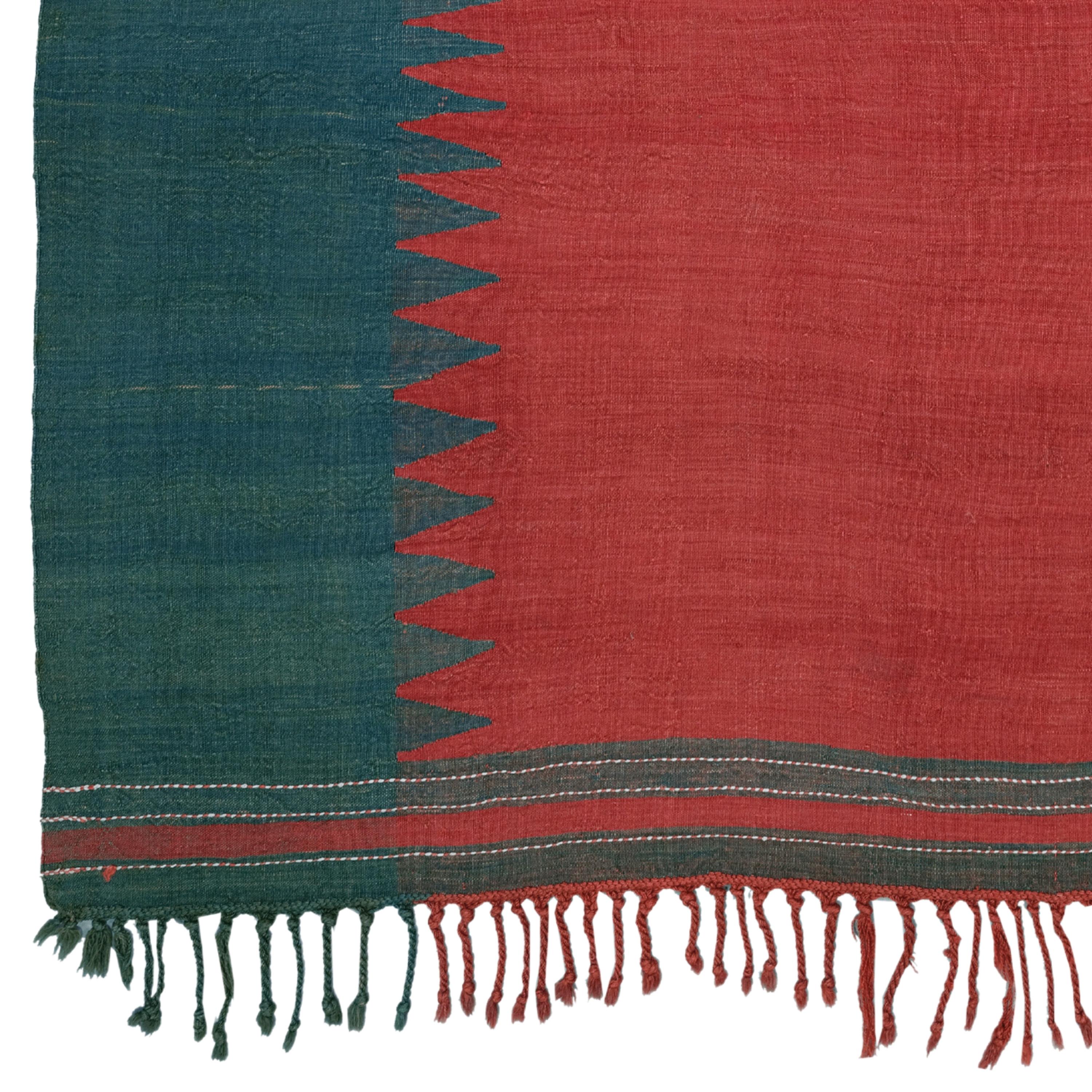 Woven in a single panel, this kilim cover is executed in just two colours. The empty red field and the equally undecorated green vertical borders are interlocked by means of sharp points – a typical design principle of Azeri textiles of this kind.