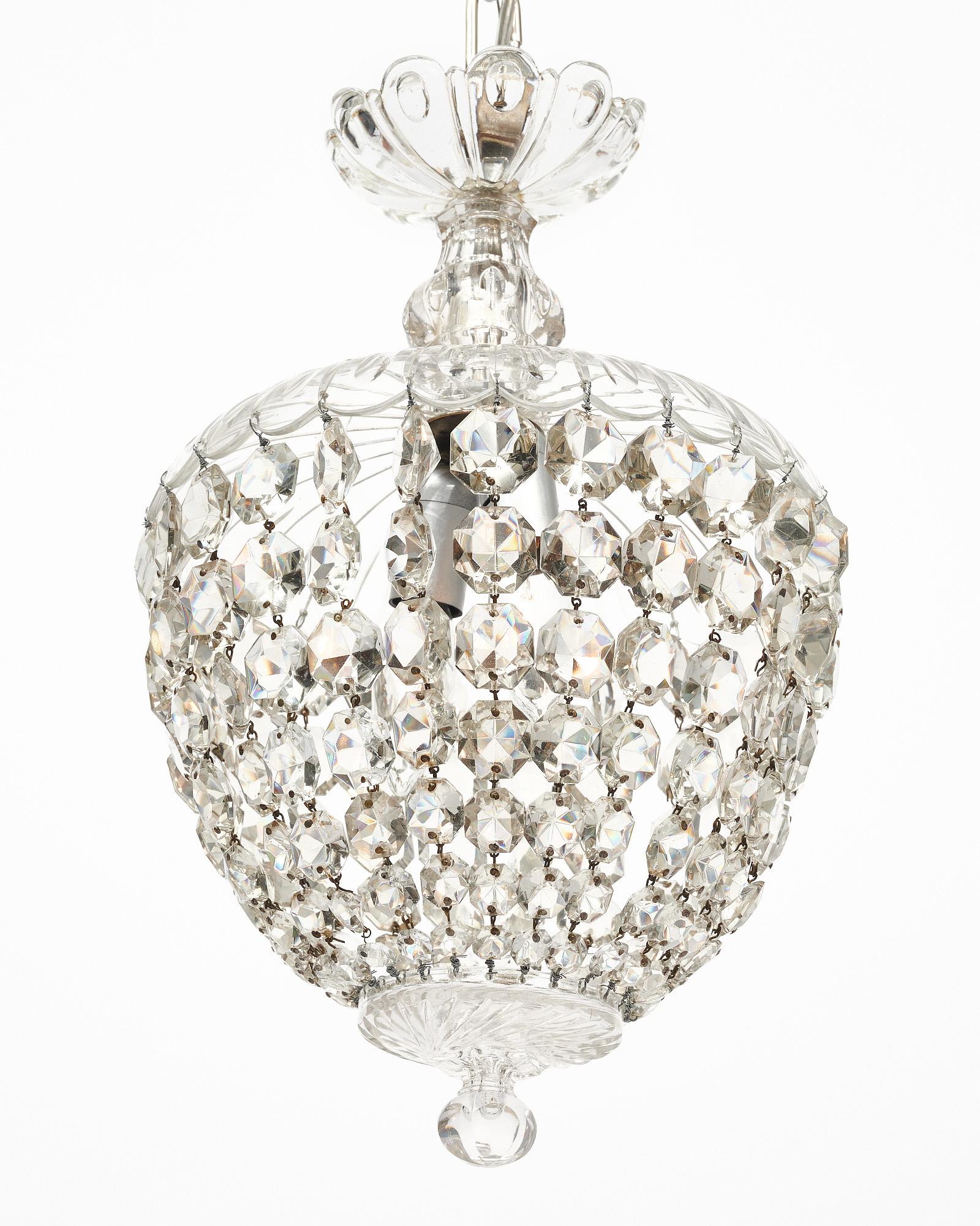 Chandelier/pendant from France in the iconic Baccarat bell shape. The crystal bell top holds strands of cut crystal elements (cabochons) that come together at the crystal finial. This piece is transparent in color. It has been newly wired to fit US