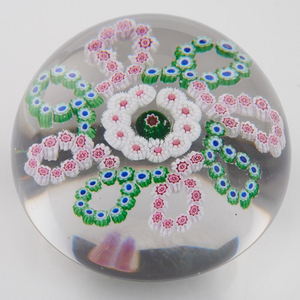 Heading : An Antique Baccarat Millefiori Garland Paperweight c1880
Date : c1880
Origin : France
Features : A millefiori garland of eight loops around a concentric ring and centre cane
Marks : None
Type : Lead
Size : 7.3cm diameter
Condition : Tiny