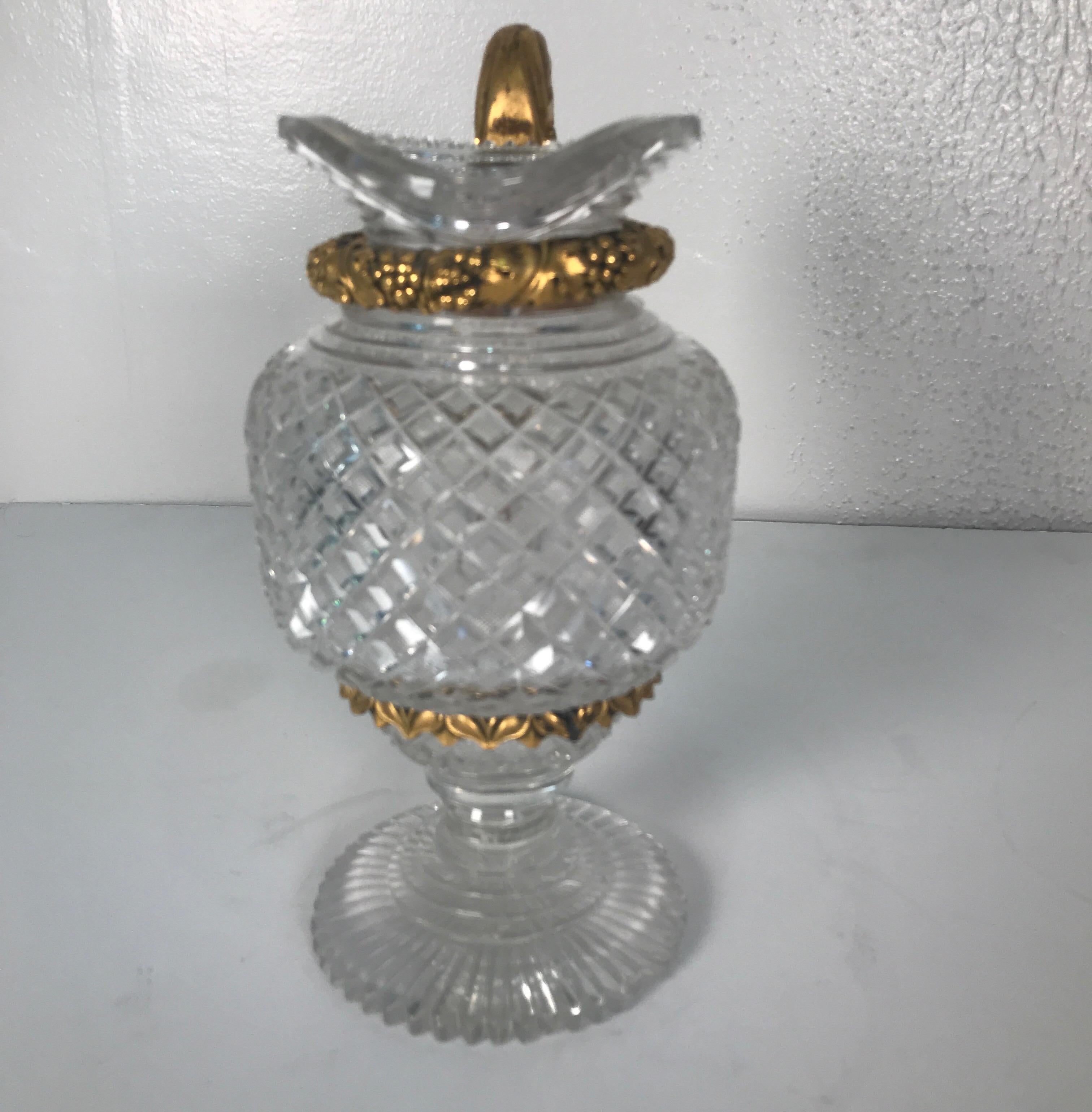 Early French cut glass pitcher attributed to Baccarat with cast gilt bronze ormolu mounts and handle. The all-over diamond cut glass body with beautifully cast bronze ring mounts and handles. The round base with a starburst pattern. There is a