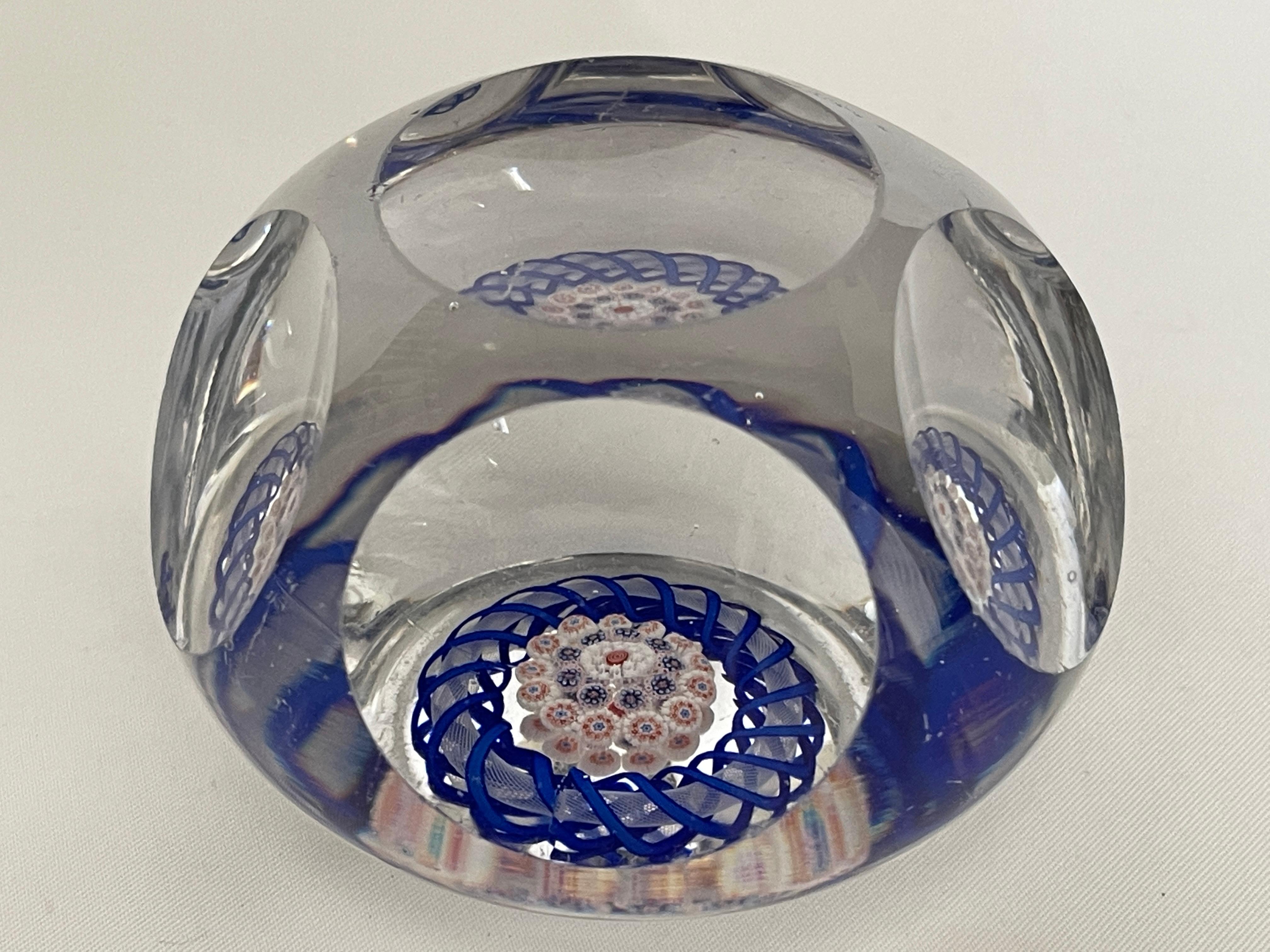 Antique Baccarat faceted art glass paperweight with closepack cane millefiori mushroom at center, surrounded with a blue torsade ribbon.
Paperweight has faceted convex circle at top and five faceted circles surrounding, which creates lovely windows