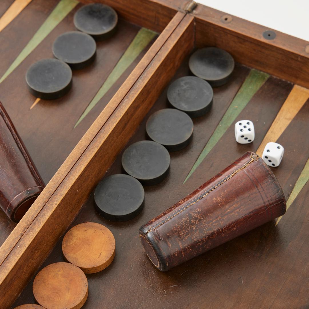 - This beautiful antique backgammon set features an original marquetry board, made by hand in France in the early 20th century.

- The inlaid wood gameboard was crafted by hand from solid walnut using traditional tongue and groove methods. Its brass