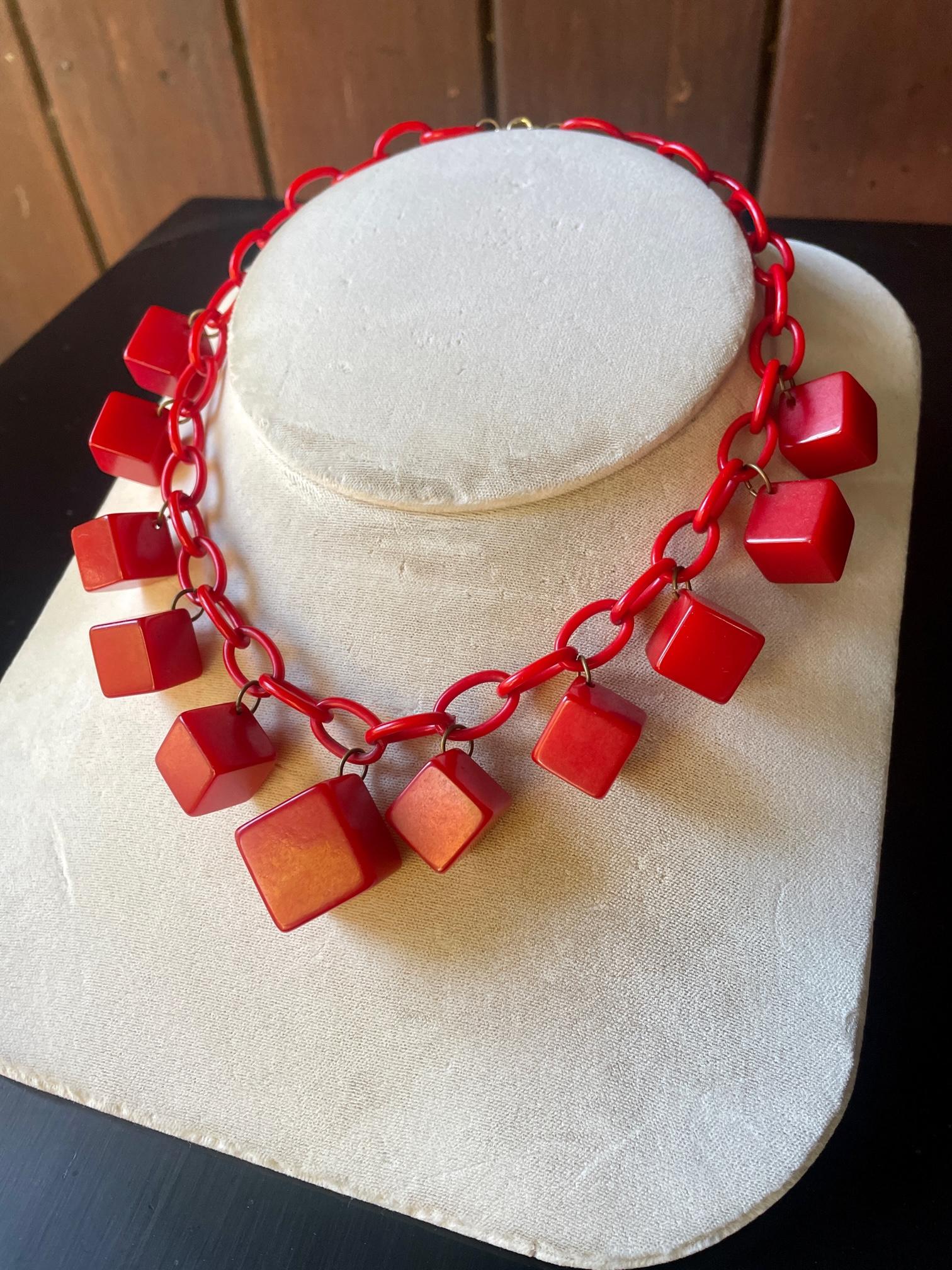 USA c.1930s. Unknown Maker. Celluloid linked chain and Bakelite cube charms.  With a good clasp, this necklace is ready to wear.

Fair Condition because one smaller cube is chipped and drilled. The original mounting hole was chipped so the charm was
