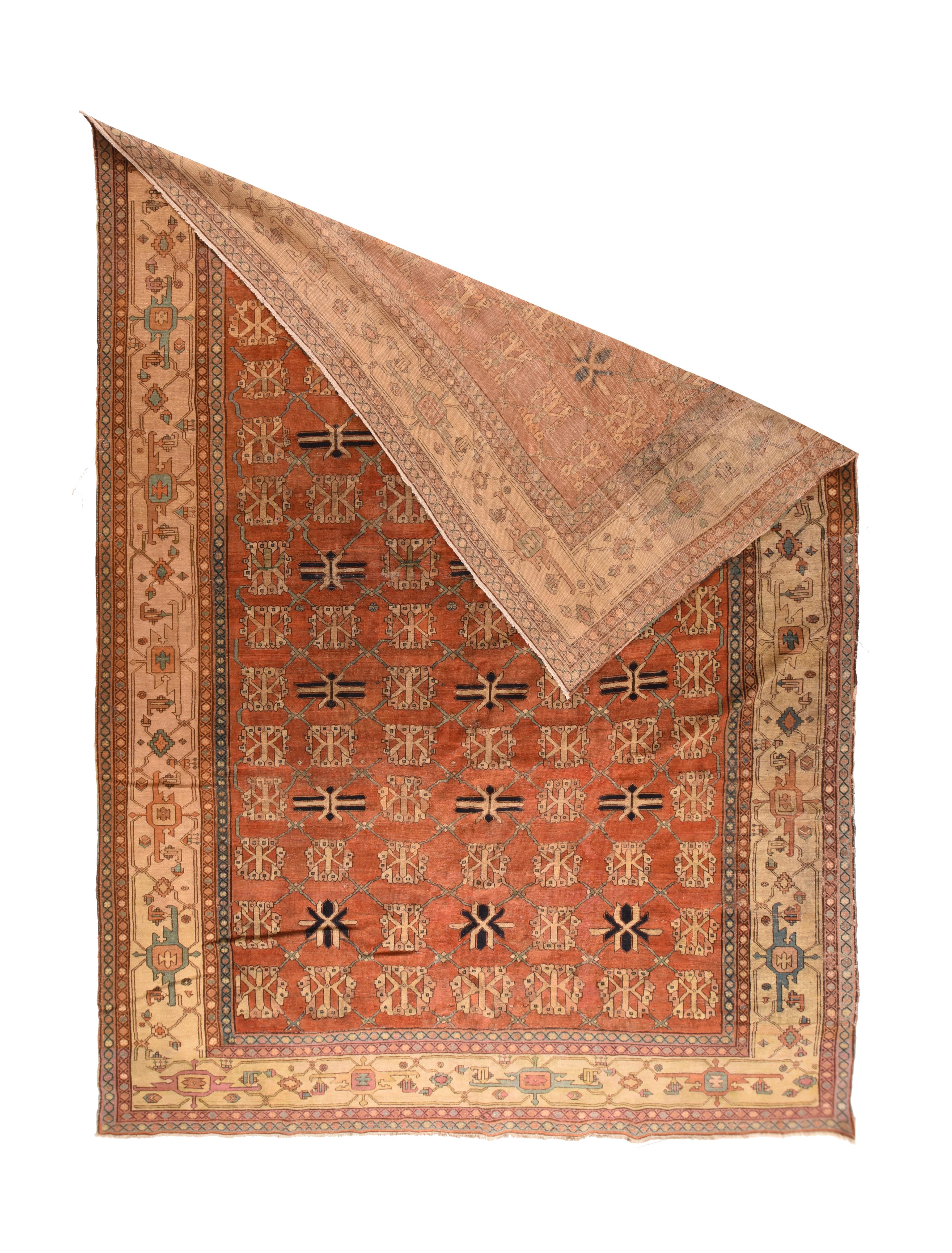 The rust field of this rustic Central Asian piece shows a seven by thirteen arrangement of repeating stylized flowers and guls accented in straw and black. The darker detailed guls are in every second row.The strip style straw-cream border is in the