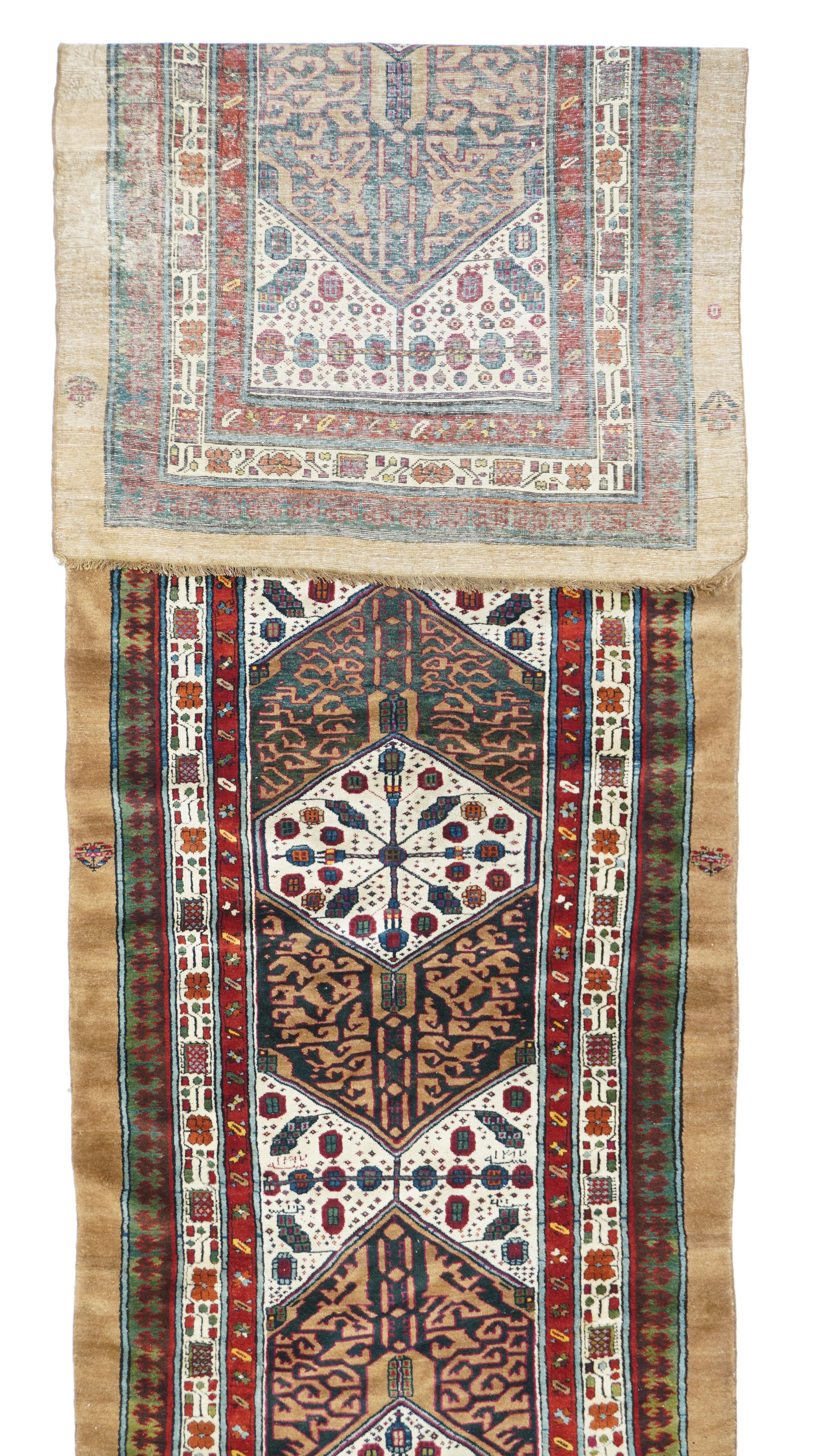 In the Sarab style, but unusually on cotton, this rustic kenare (runner) features three hexagonal camel Ð tone panels enclosing smaller ecru hexagons, with en suite trapezoid fillers. Dark blue mazeworks in the camel sections. Virtually plain