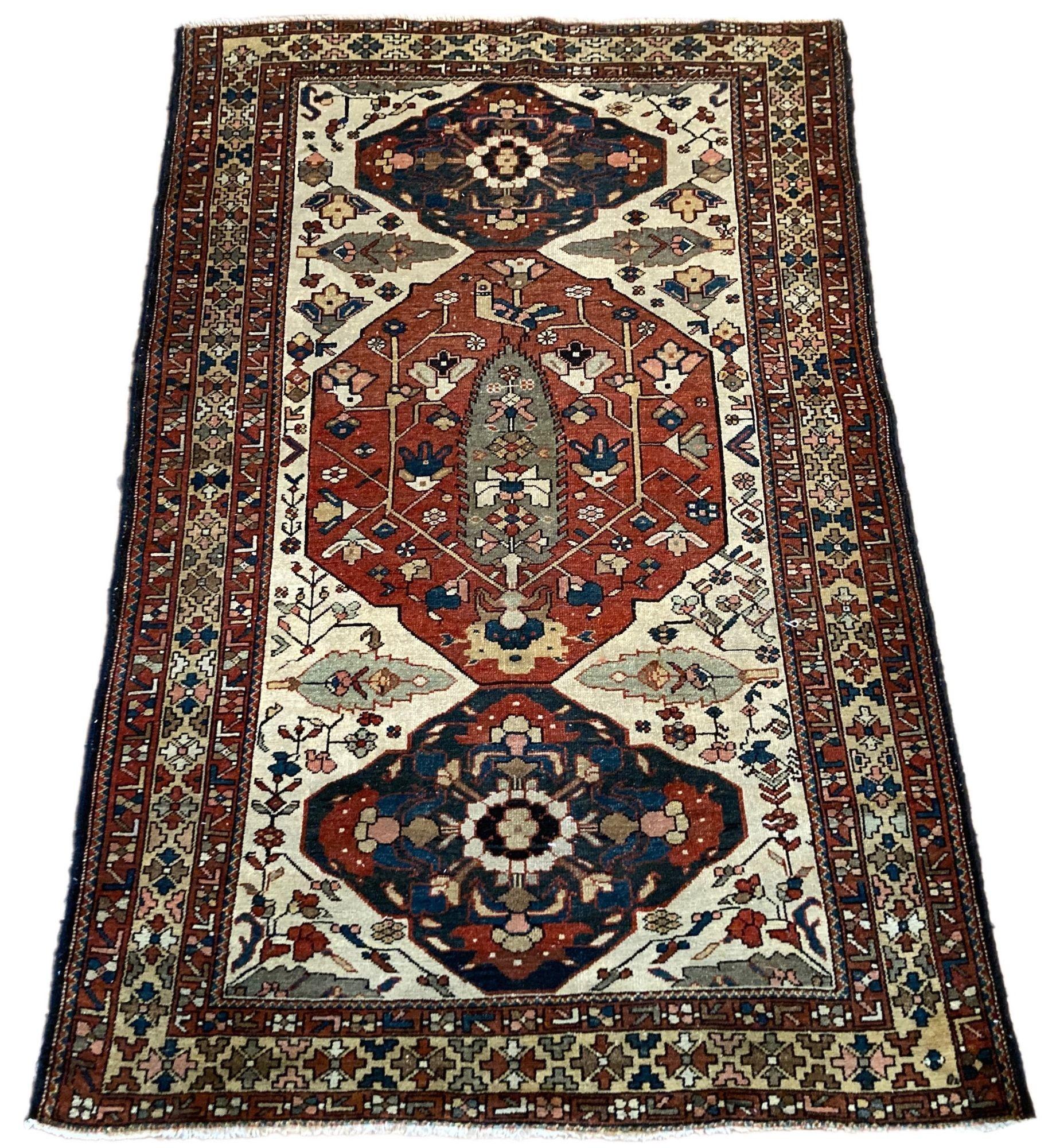 A fabulous antique Bakhtiar rug, handwoven circa 1900. The design features a terracotta medallion with a central cypress tree flanked by two smaller indigo medallions on a rare ivory field. A beautifully simple design with great secondary colours of