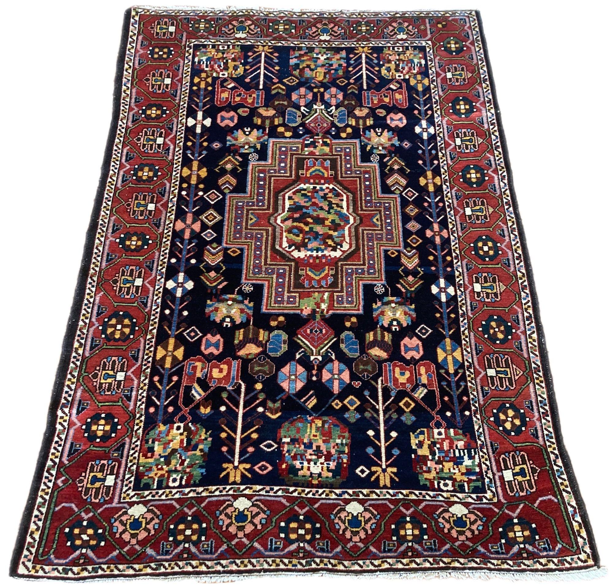 A beautiful antique Bakhtiar rug, hand woven circa 1910 with a single medallion floral design on a deep indigo field and terracotta border. Wonderful secondary colours of pinks, greens and golds and a highly decorative rug. The rug is slightly