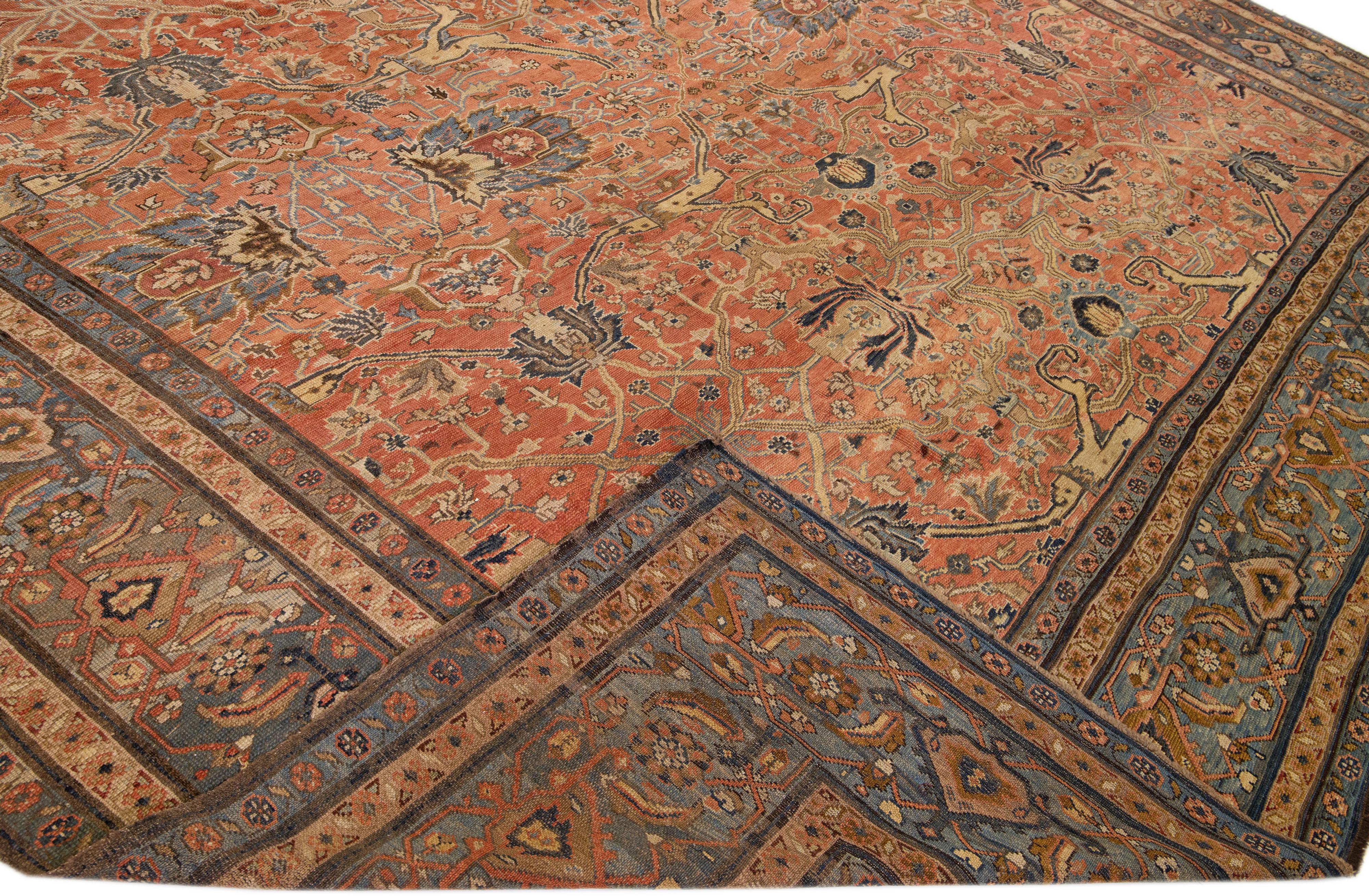 Beautiful antique Bakshaish hand-knotted wool rug with a rust field. This piece has a blue frame and beige accents on a gorgeous Classic all-over floral design.

This rug measures 14'4