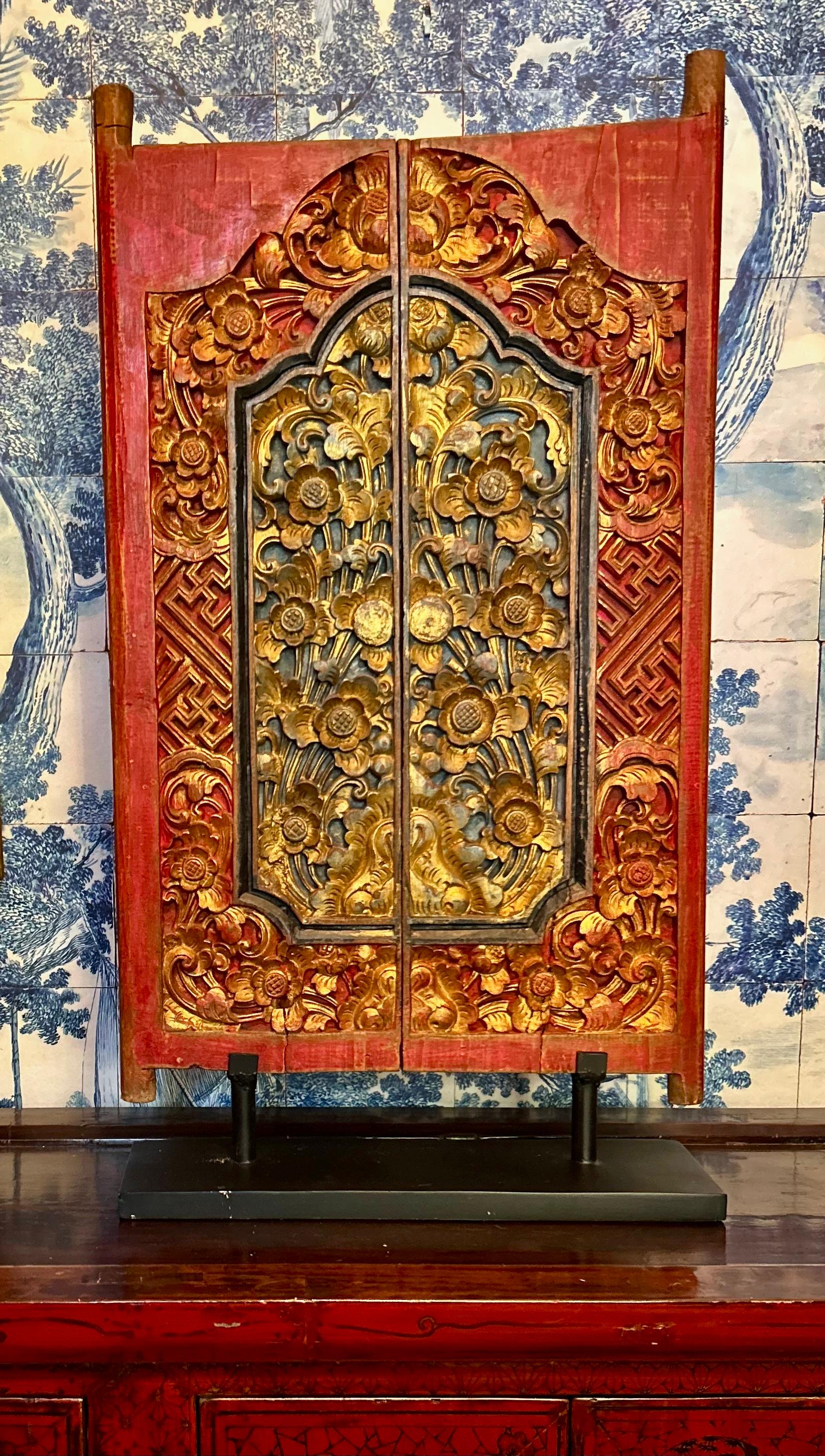Schöne antike balinesische Tür, wahrscheinlich 19. Jahrhundert. Diese Tür/Fensterladen wurde in aufwändiger Handarbeit mit Ranken, Blumen und Spalieren geschnitzt, mit vergoldeten Akzenten auf blauem und rotem Grund. Die beiden Platten der Tür