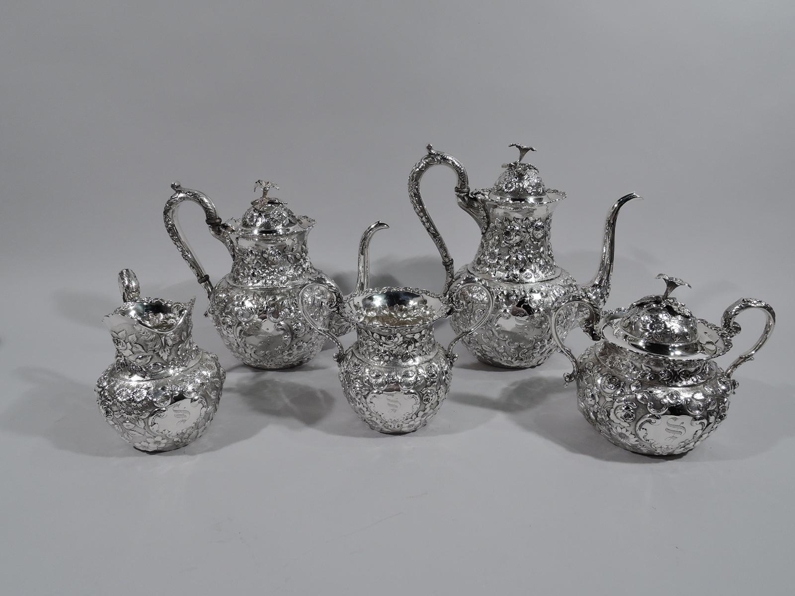 Five-piece sterling silver tea and coffee set with floral repousse. Made by AG Schultz & Co. in Baltimore, circa 1910. This set comprises coffeepot, teapot, creamer, sugar, and waste bowl.

Each: Round with high-looping leaf-capped S-scroll