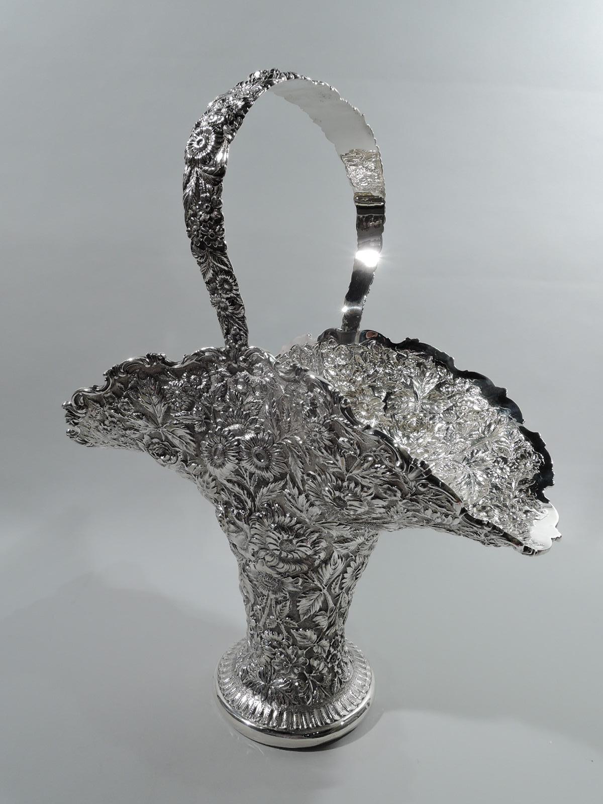 Victorian sterling silver basket. Made by the Stieff Company in Baltimore, ca 1910. Wide and ovoid mouth with fixed c-scroll handle and cylindrical body flowing into spread foot. Dense allover floral repousse on stippled ground. Mouth rim has