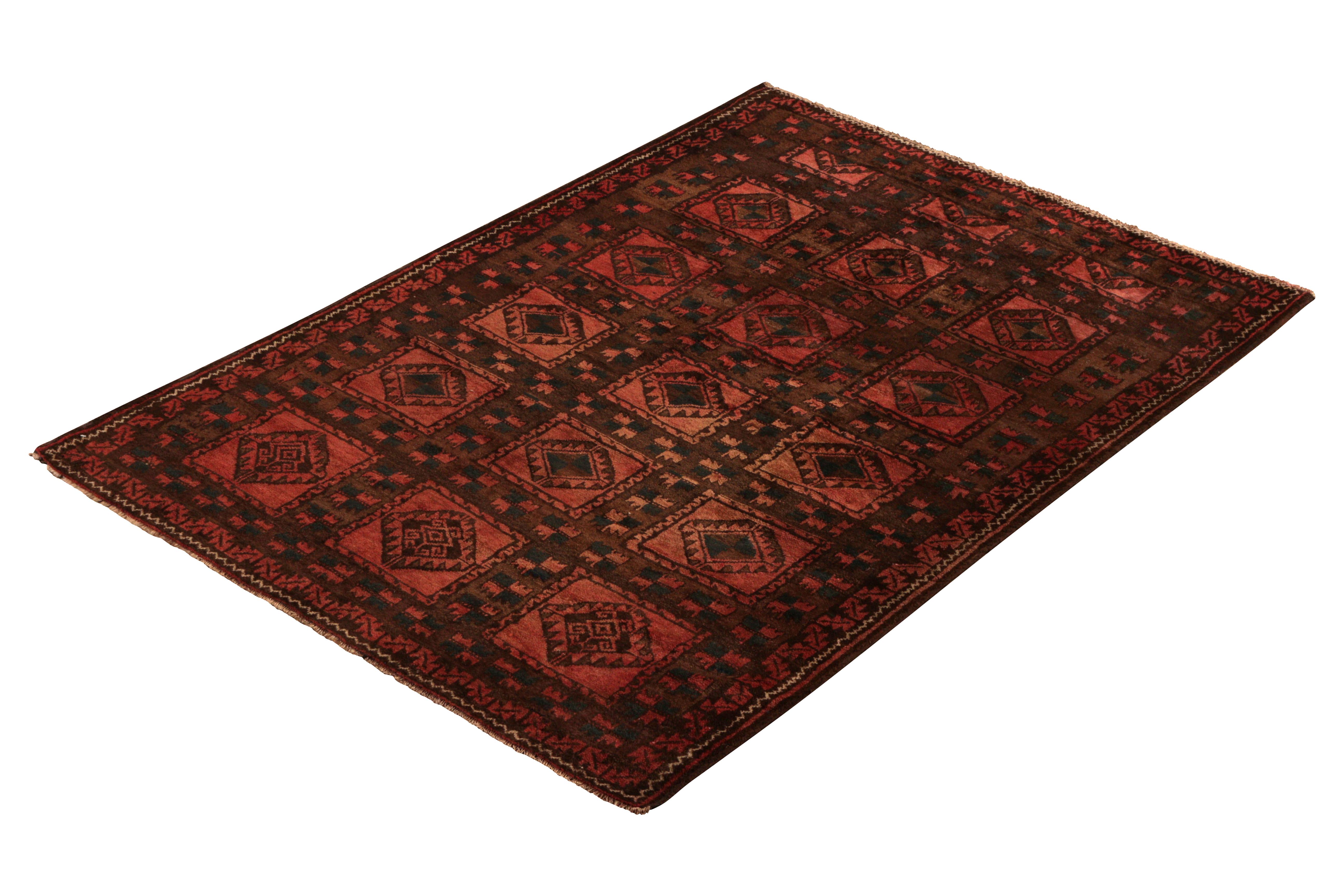 Hand knotted in wool originating circa 1910-1920, this antique rug connotes an tribal Baluch rug design with a unique emphasis on an atypical pink-red colorway. The subtle variations in this colorway dye lend the more traditional all-over medallion