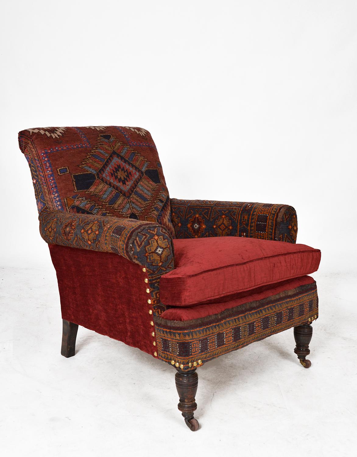 A sumptuous antique ‘Baluch’ carpet chair sat on front castors, covered in garnet coloured velvet with matching feather filled cushion. Professionally upholstered in two antique Baluch rugs; one with a multi-coloured geometric pattern on the back