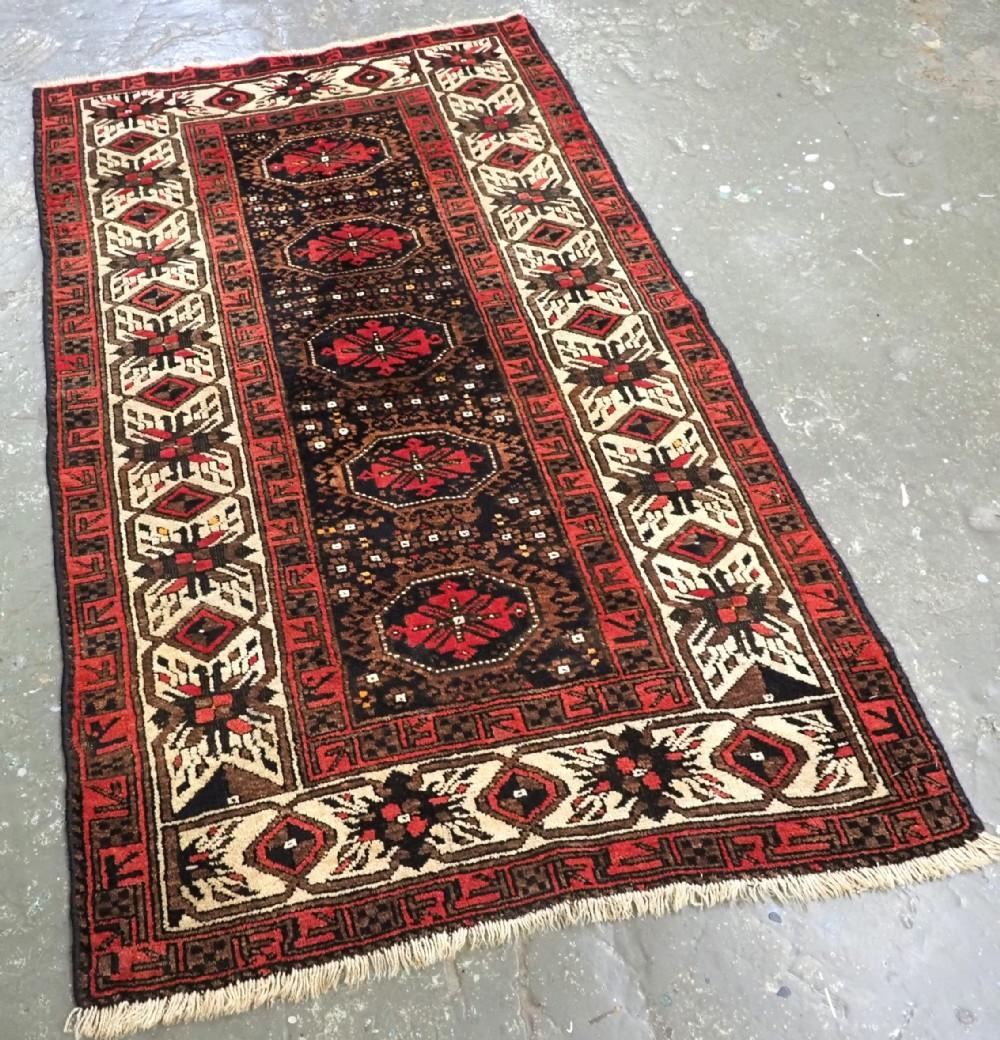 Antico tappeto arabo Baluch di scarso design proveniente dalla regione di Ferdows
Circa 1900

Il tappeto presenta un disegno di cinque medaglioni su un fondo blu indaco scuro; ogni medaglione contiene un disegno di gul turcomanni su un campo di