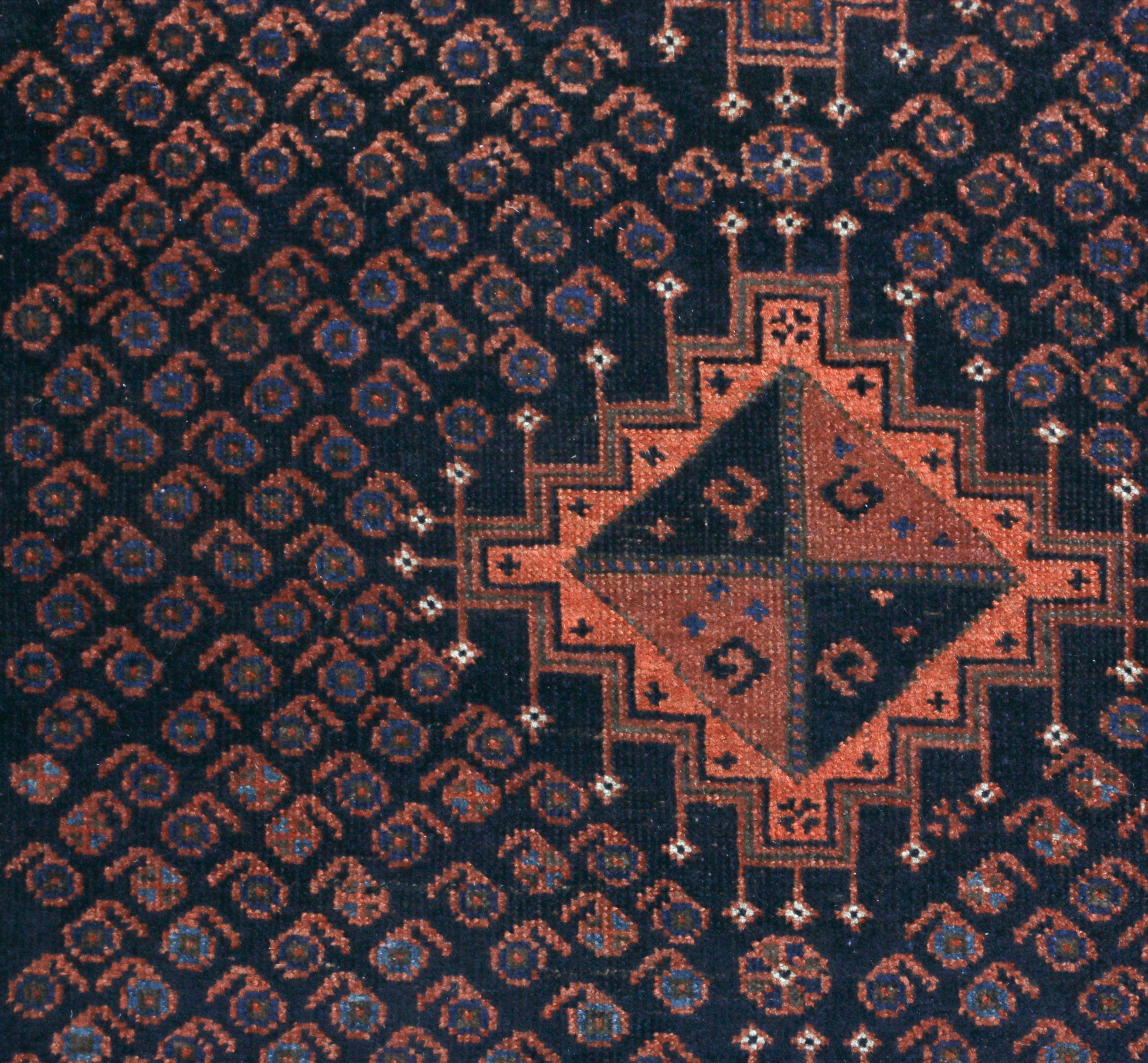 Dieser antike Übergangsperserteppich aus Wolle stammt aus Persien aus dem Jahr 1910 und weist ein hervorragendes Belutsch-Muster auf. Das aus hochwertiger Wolle handgeknüpfte Feldmuster im Medaillon-Stil zeigt ein Dyrnak-Muster mit Elementen von