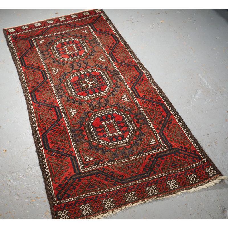 Antique Baluch tribal rug woven by the Salar Khani sub tribe.

The rug has three large turreted guls on a soft brown coloured ground, the rug is framed by a traditional Baluch border. At each end of the rug there is an interesting piled panel.

The