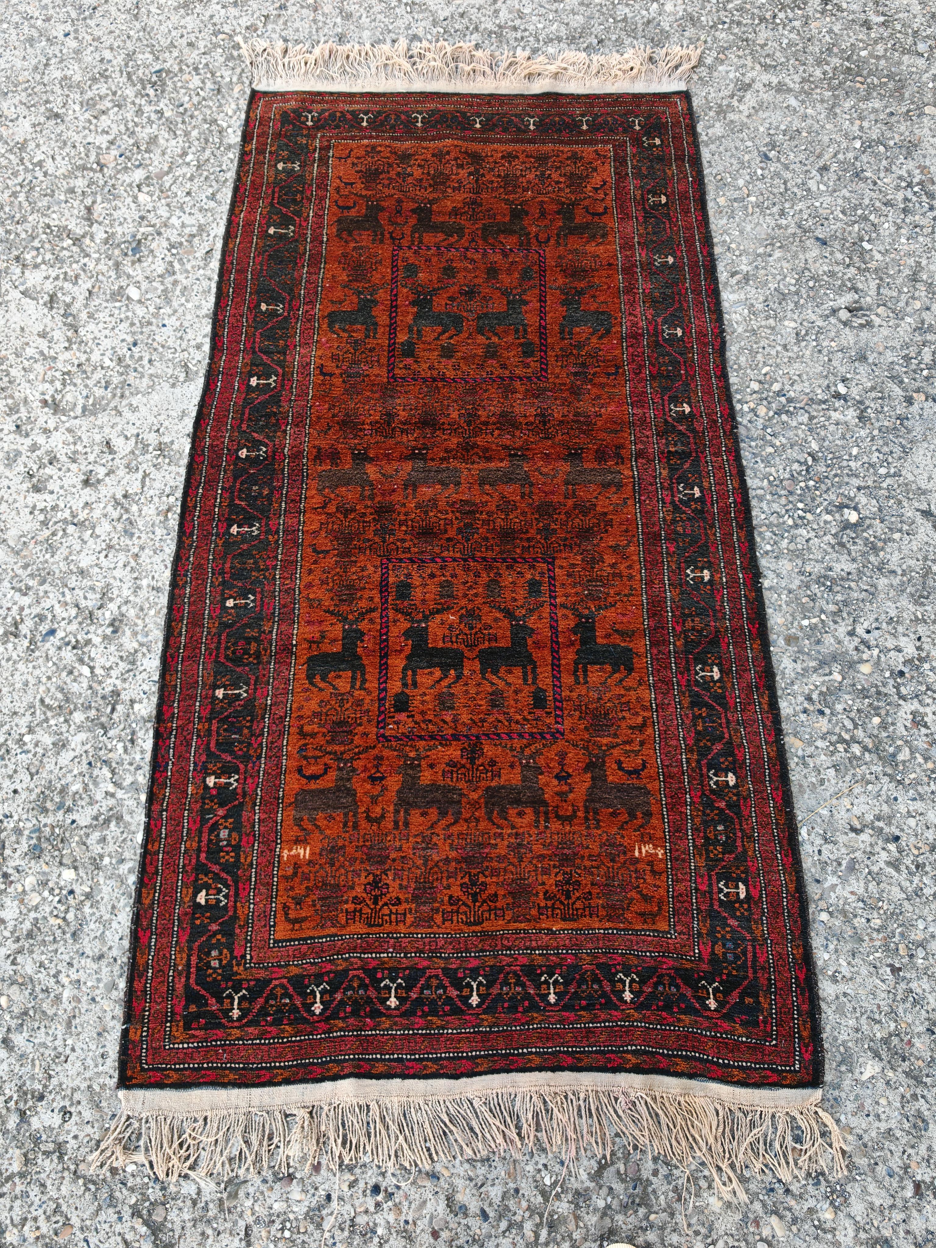 Vous trouverez dans cette liste un magnifique tapis ancien noué à la main de Baluch, présentant des motifs géométriques et stylisés de cerfs dans des tons rouges, orange et noirs profonds. Il est tissé par les tribus nomades Baluch, qui vivent dans
