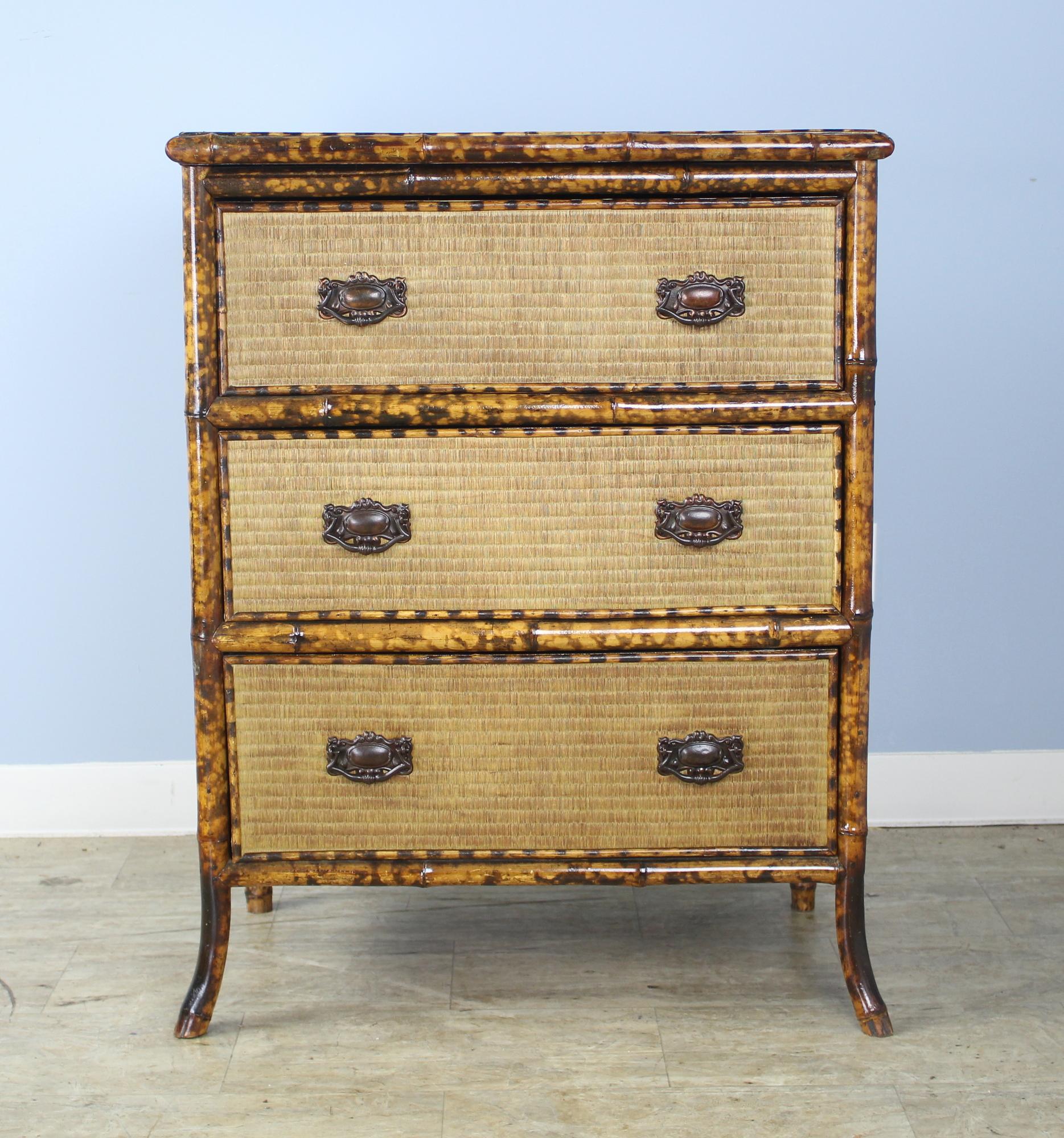 A smart and highly decorative bamboo and rattan chest of drawers with a chinoiserie lacquered op in very good condition. The rattan has been lightly recolored, as has the vibrant bamboo. Lively black and red and gold pattern on the top with floral