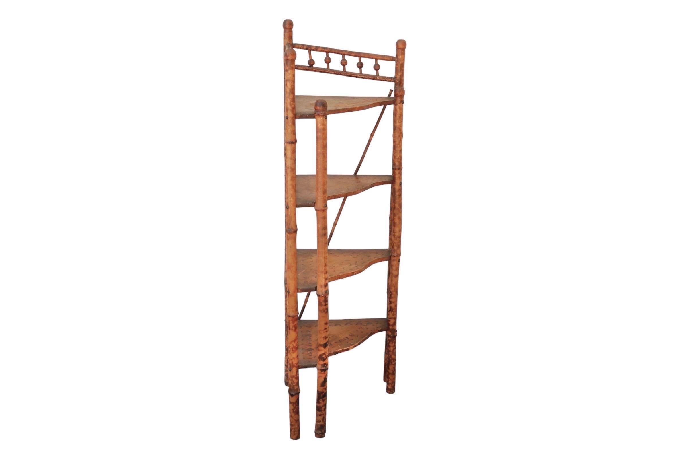 An antique faux tortoise shell corner etagere made of bamboo. Four serpentine carved shelves and five bamboo supports are painted with a dappled “faux tortoise shell” finish. The top shelf is decorated with a pencil wood bamboo gallery rail, with
