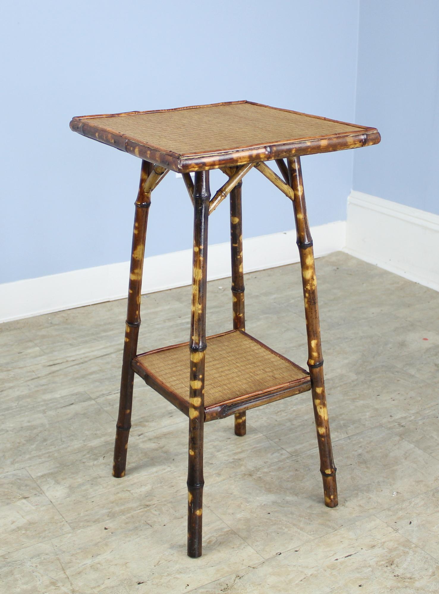 A small bamboo side table with top and bottom shelf of tightly woven rattan in fabulous antique condition. The painted legs still retain their vibrancy. Measurements below are for the entire table. The top measures: 14 inches by 14 inches. Sweet!