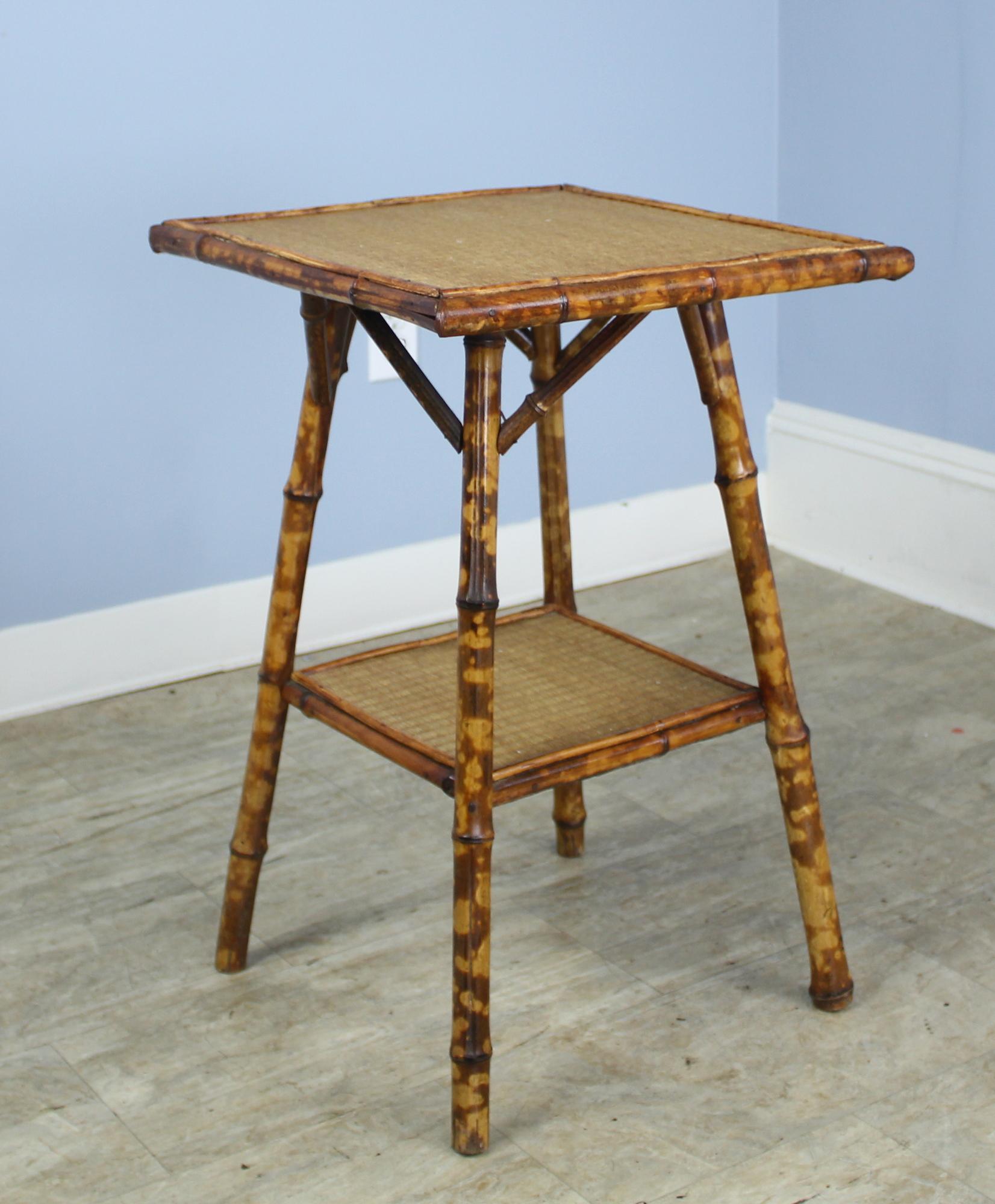An elegant bamboo side table, with wonderful antique color and patina. The woven top and lower shelf are in very good antique condition as are the dainty legs. Charming!