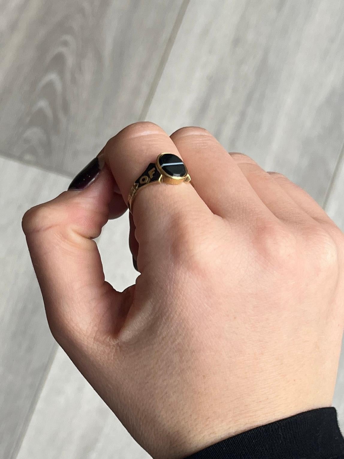 The gorgeous banded agate stone in this memorial ring is jet black and has a stylish white line straight through the middle of it. Modelled in 18ct gold and hallmarked London 1853. The shoulders make up the message which is around the band, which is
