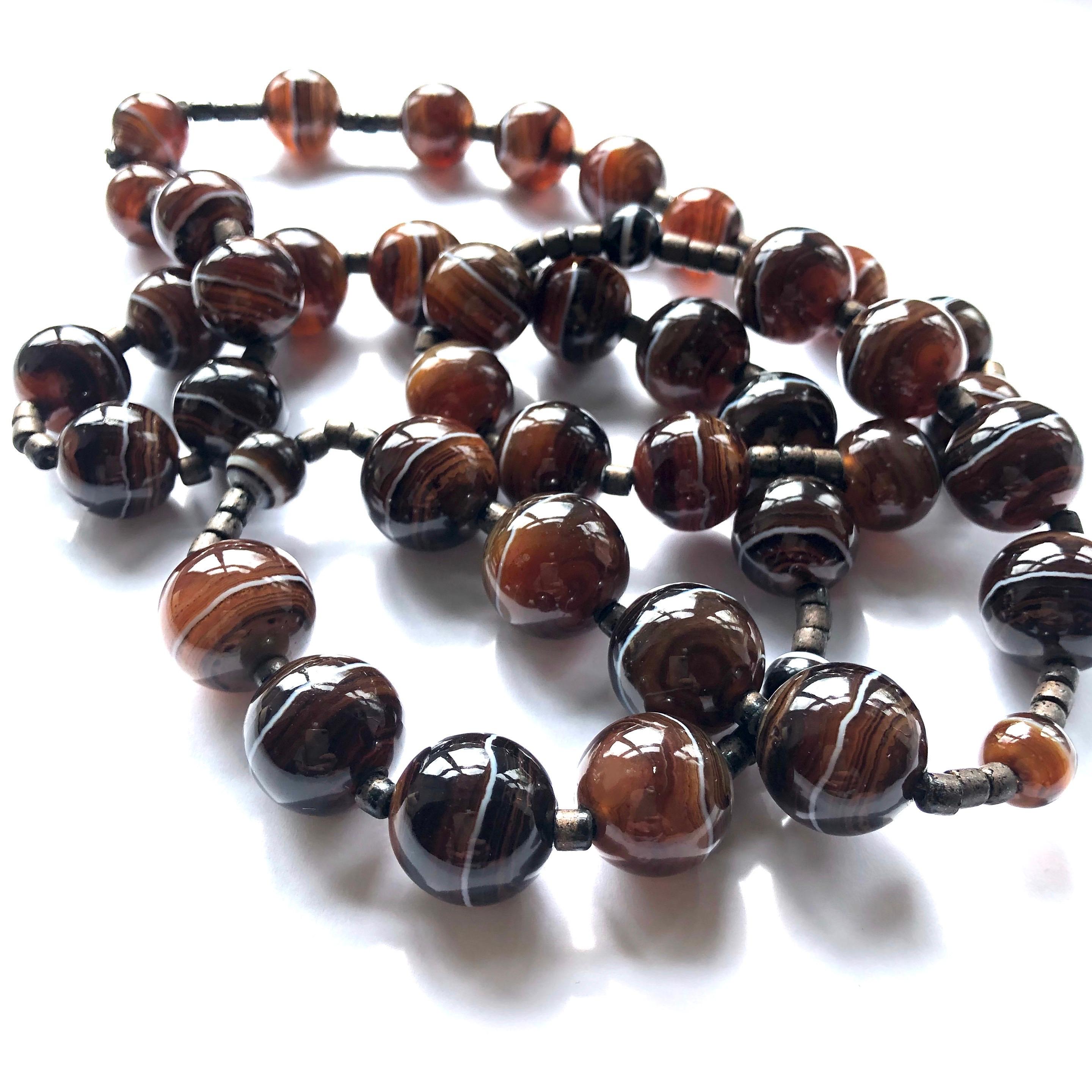 The banded agate beads which make up this necklace are a mix of black and brown with all tones in-between! The bright white rings around the beads curve and wave and are beautiful. 

Length: 35inches 

Weight: 192g