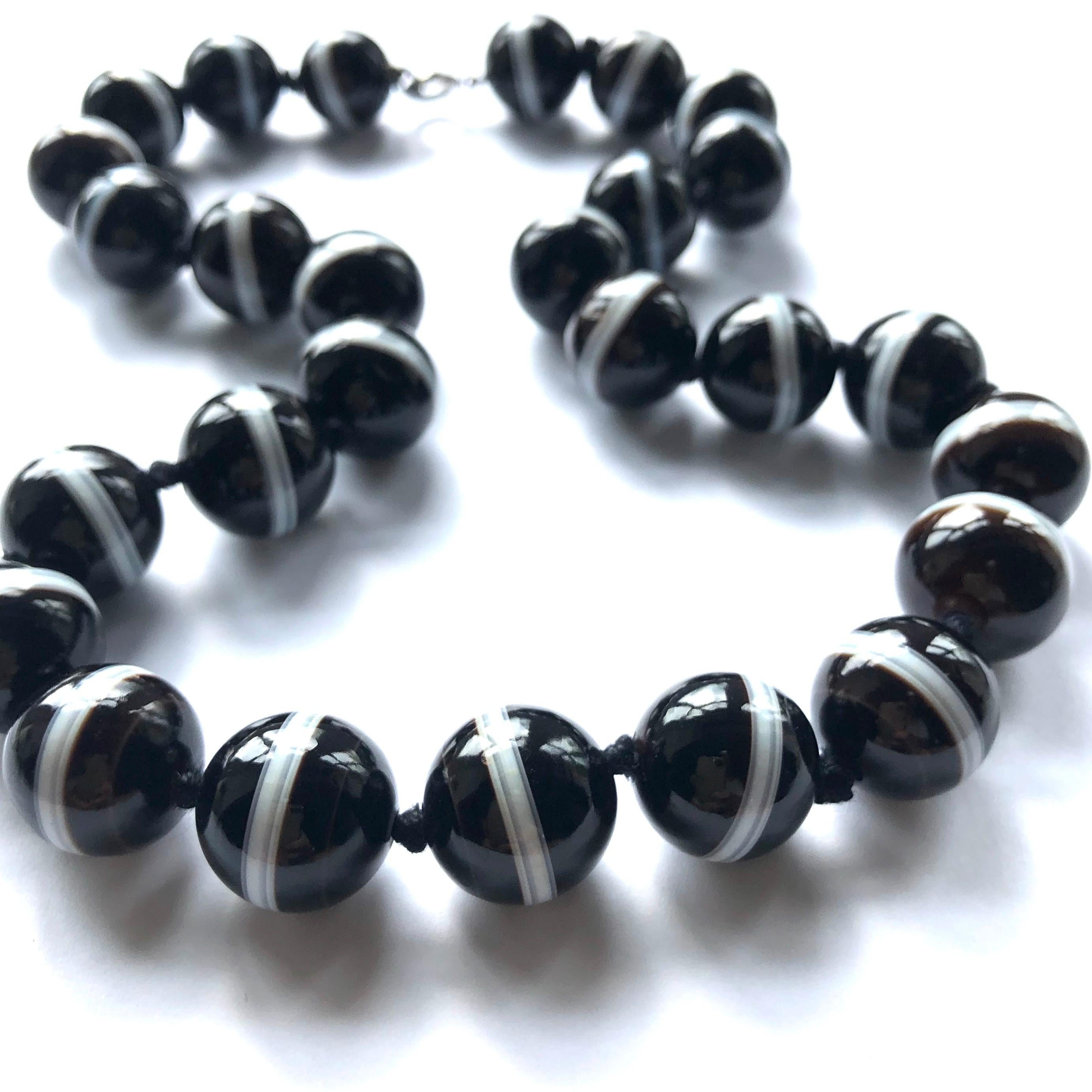 The black agate beads are gorgeous and glossy. The white band which rubs through each band is chunky and looks bright next to the dark bead. 

Length: 18inches 

Weight: 121g