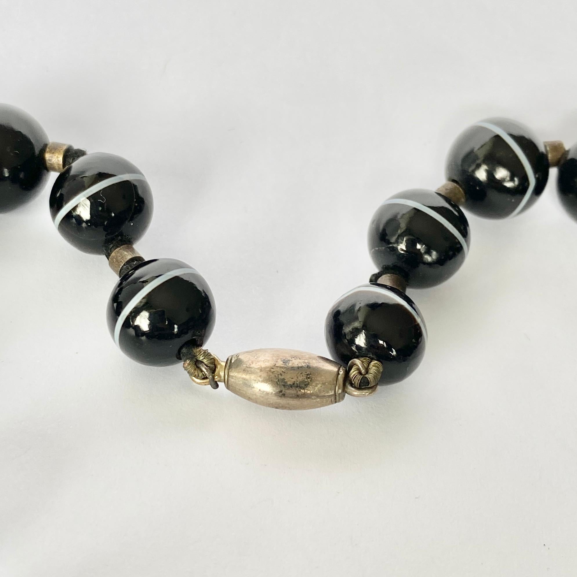 The black agate beads are gorgeous and glossy. The white band which runs through each band is chunky and looks bright next to the dark bead. 

Length: 36.5cm 

Weight: 77.5