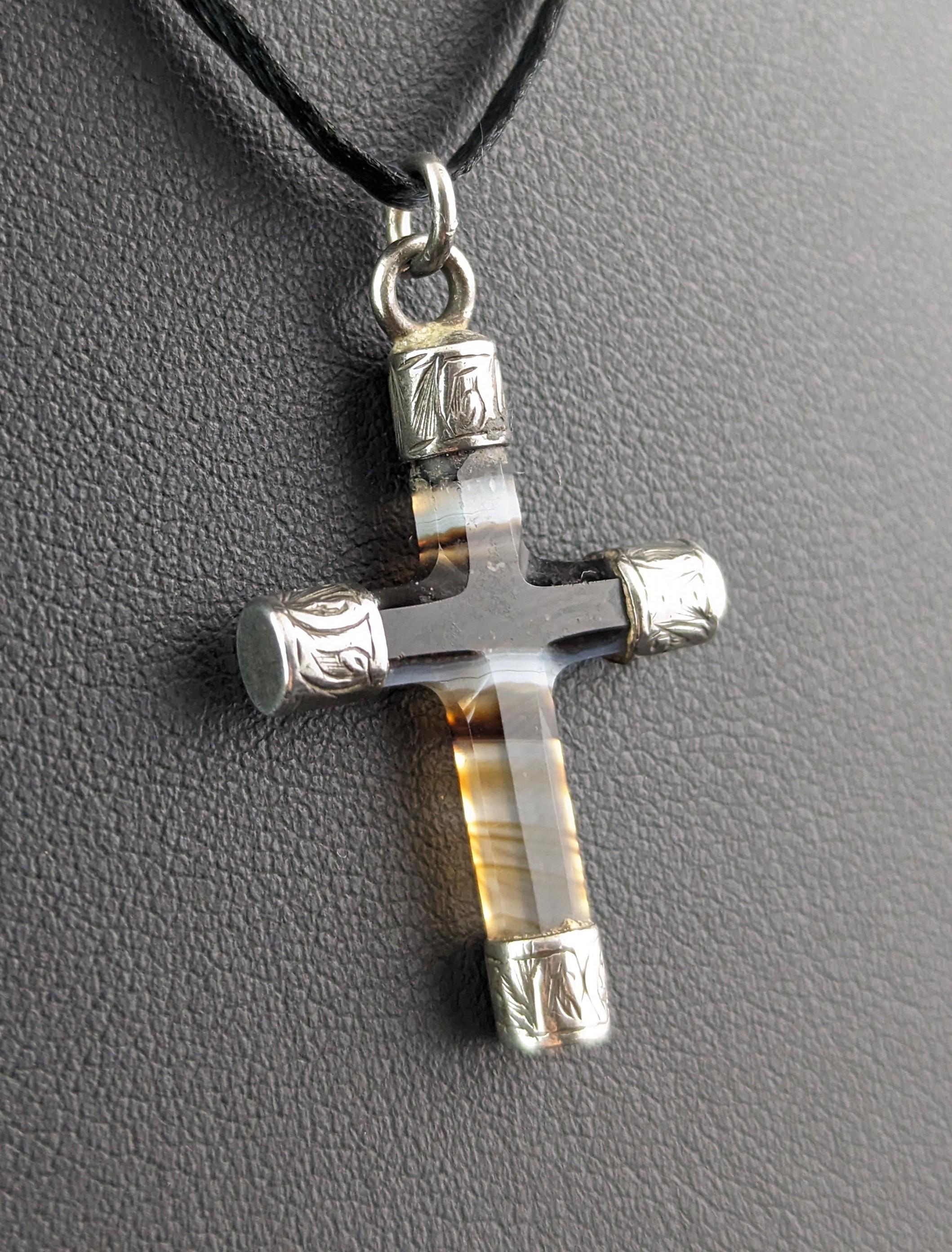 A gorgeous and dainty antique banded agate Cross pendant.

Lovely bands of varying shades running through the Carnelian from deep black to clear.

It has a sterling silver end caps which are lightly engraved and a silver bale through the top for