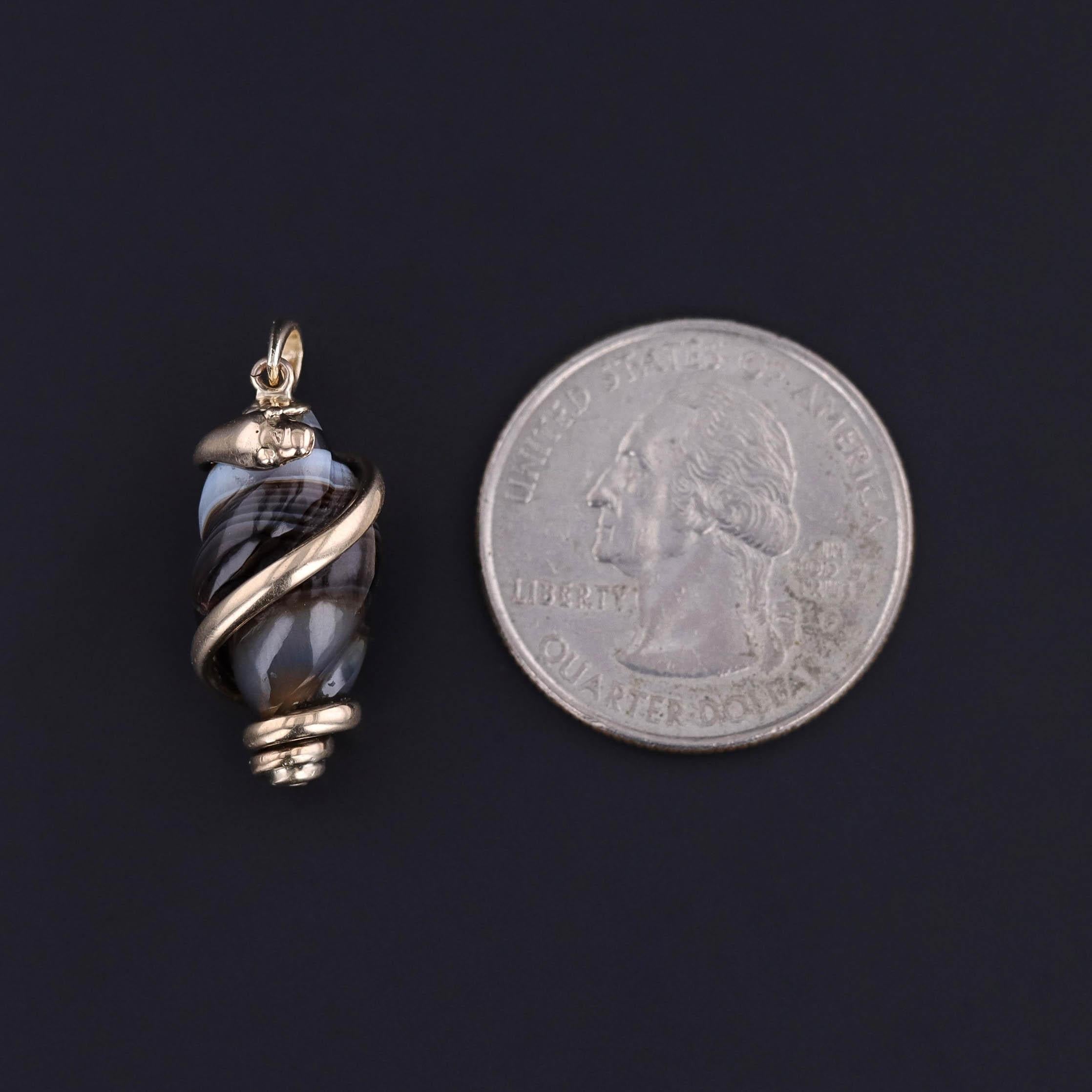 Emblème frappant de l'amour éternel, de la sagesse et de la transformation, ce pendentif antique présente un serpent en or 9ct finement sculpté, enroulé gracieusement autour d'une agate polie. L'agate naturelle - riche en stries terreuses - sert de