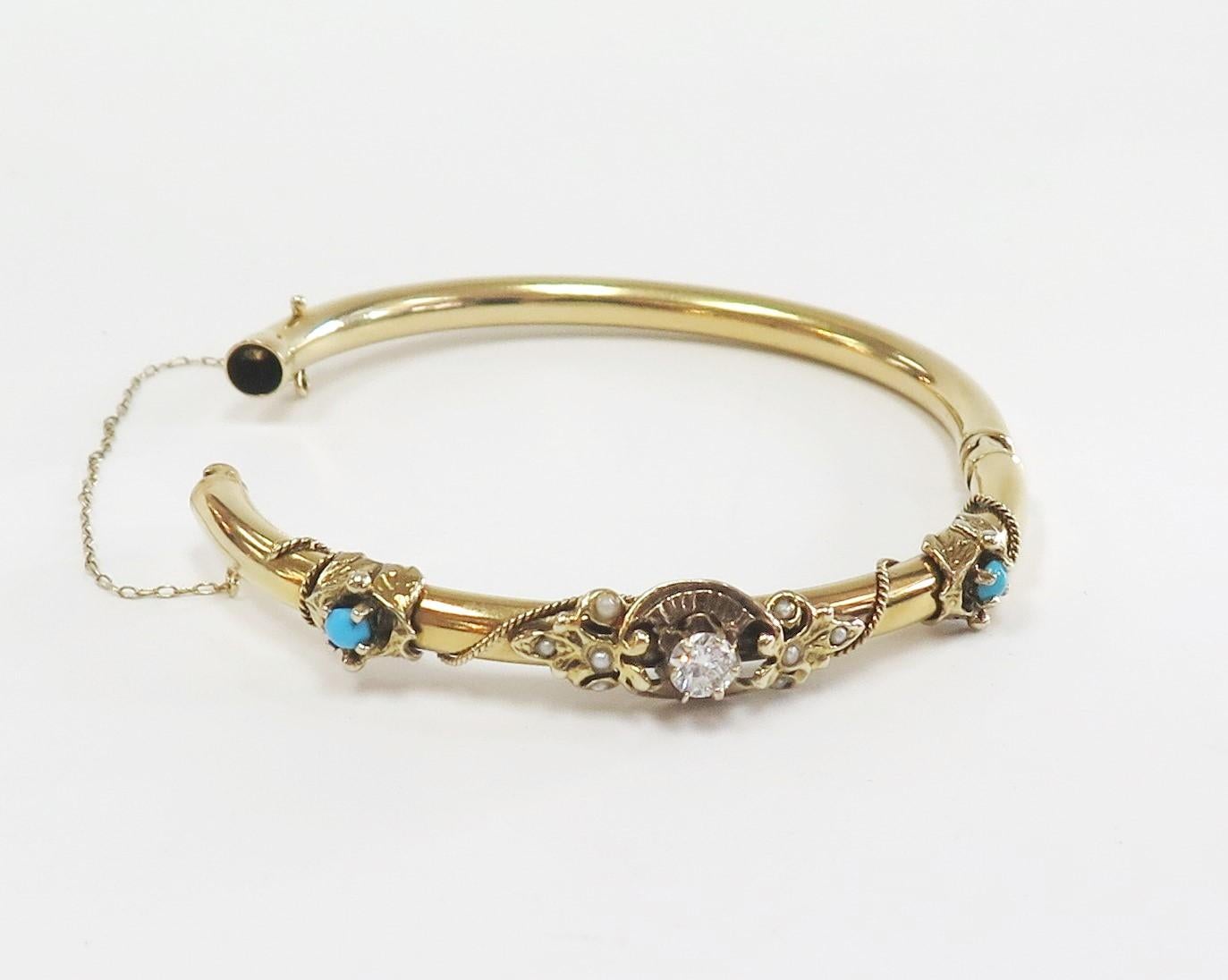 This lovely antique Victorian tubular hinged bangle is 14 karat yellow gold. Set with one center Round Diamond weighing 0.35 Carat, there are 2 side 3mm Turquoise Cabochons and several seed pearls set into a fleur de lis style design next to the