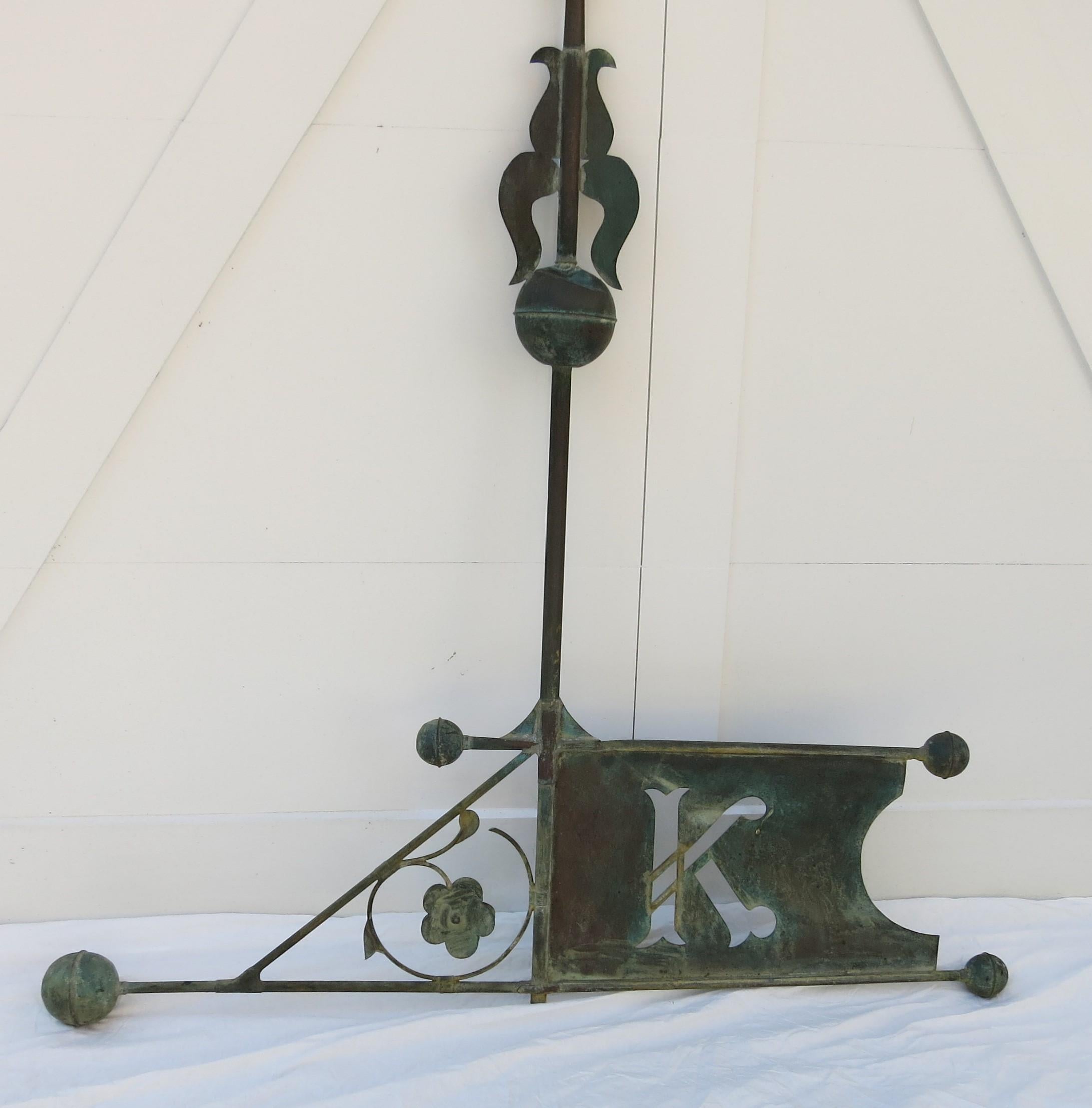 Large size and beautiful patina, this letter K bannerette weathervane comes from the Boston Massachusetts area. It is 66' high and 55' wide. There is a break to the top point held together by a dowel. One crease to the top ball and expected wear and