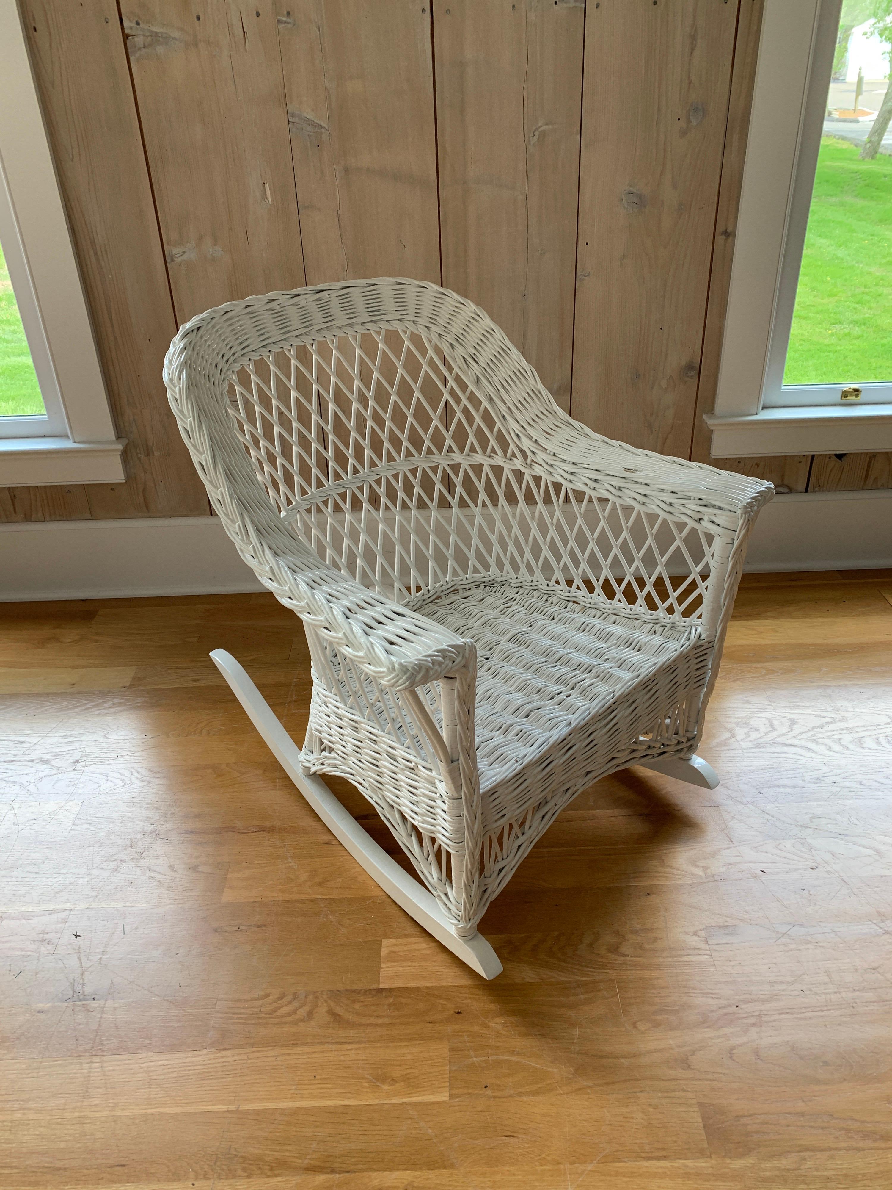 A vintage wicker rocker in the bar harbor weave woven of willow and freshly painted white. This piece measures 27.5” wide, 34” deep and 32” tall.