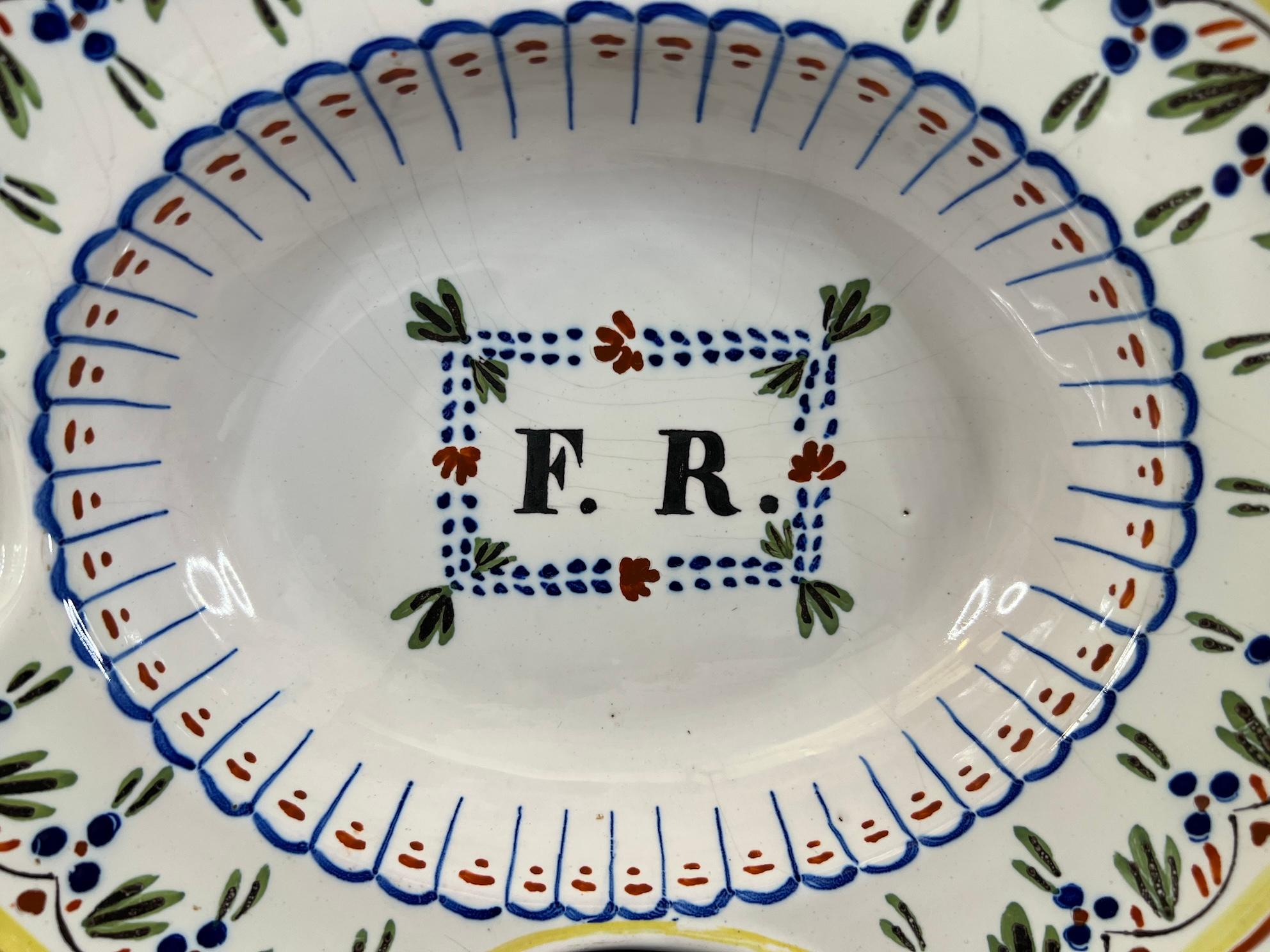 Ancient shaving dish from Nevers Auxerre with a cartouche at the center bearing the initials monogram F R. The dish is beautifully decorated.  In good condition with a chip in the enamel on the edge.  

Dimensions:  28cm x 24cm (11.02 inches x 9.45