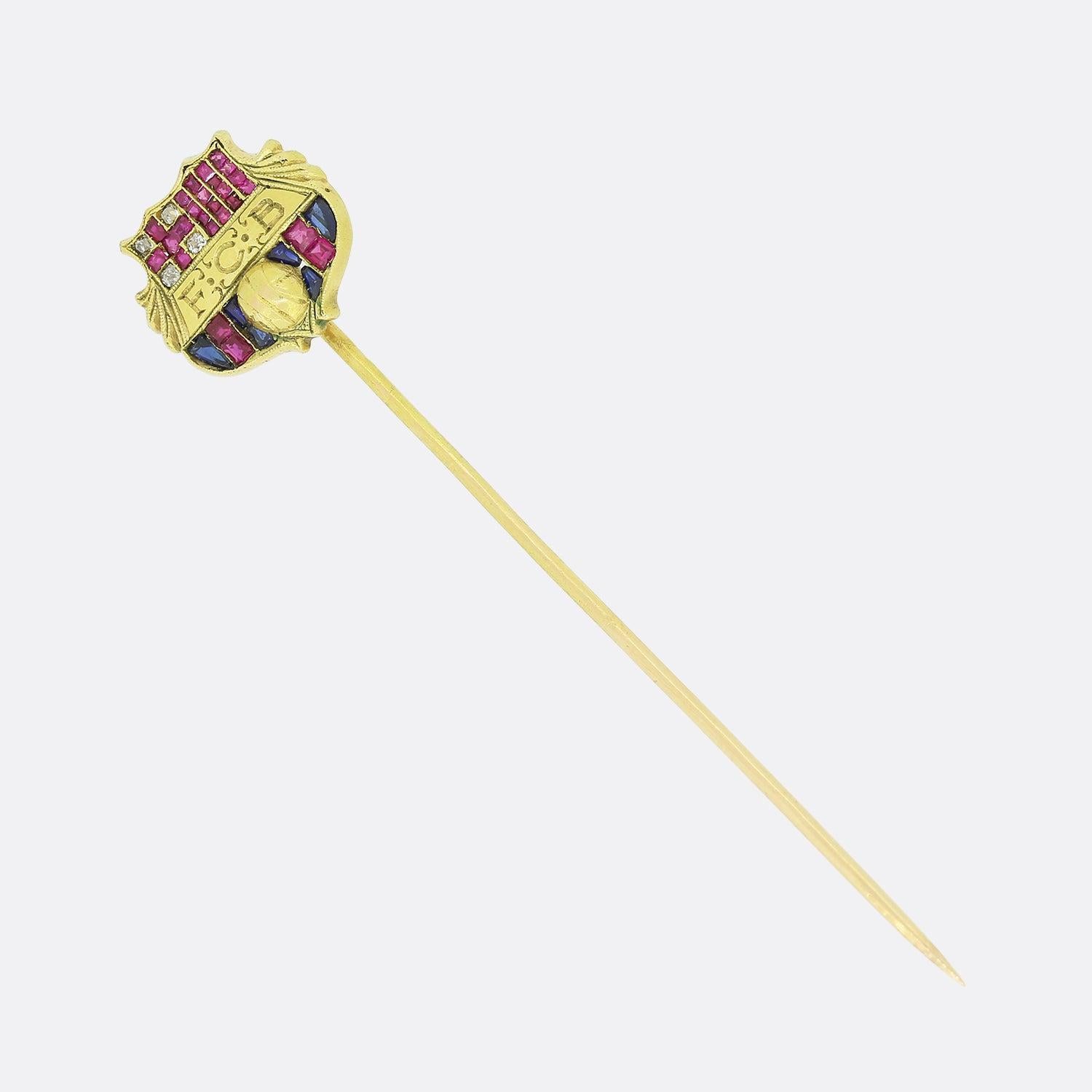 Aquí tenemos un raro y excepcional alfiler de gancho de principios del siglo XX. La cabeza está diseñada al estilo del escudo del FC Barcelona y los colores se han formado utilizando rubíes birmanos, diamantes blancos y zafiros azules. Las piedras