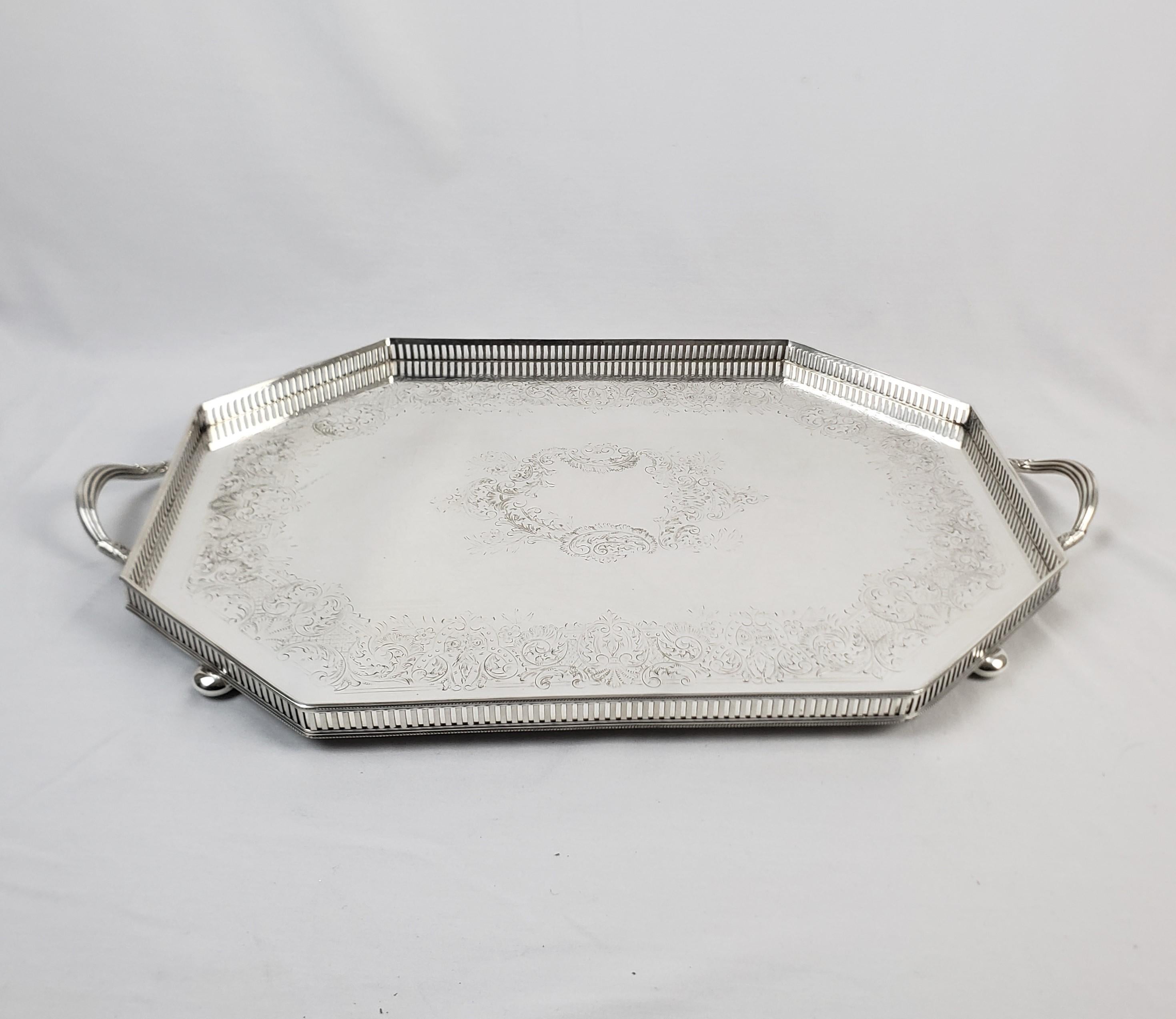This antique serving tray was made by the well known Barker Ellis Silver Company of England and dates to approximately 1900 and done in the period Edwardian style. The tray is composed of silver plate with a small pierced gallery and engraved