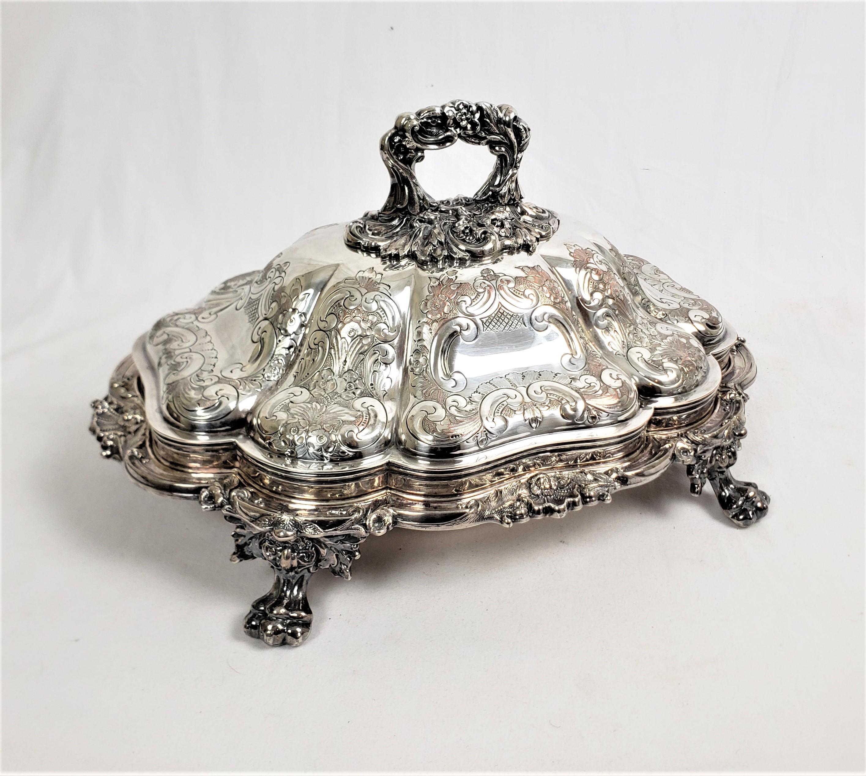This antique silver plated covered server was made by the well known Barker Ellis Silver Company of England in approximately 1912 and done in a Victorian style. This entree server has a raised scalloped dome shaped top with ornate stylized formal