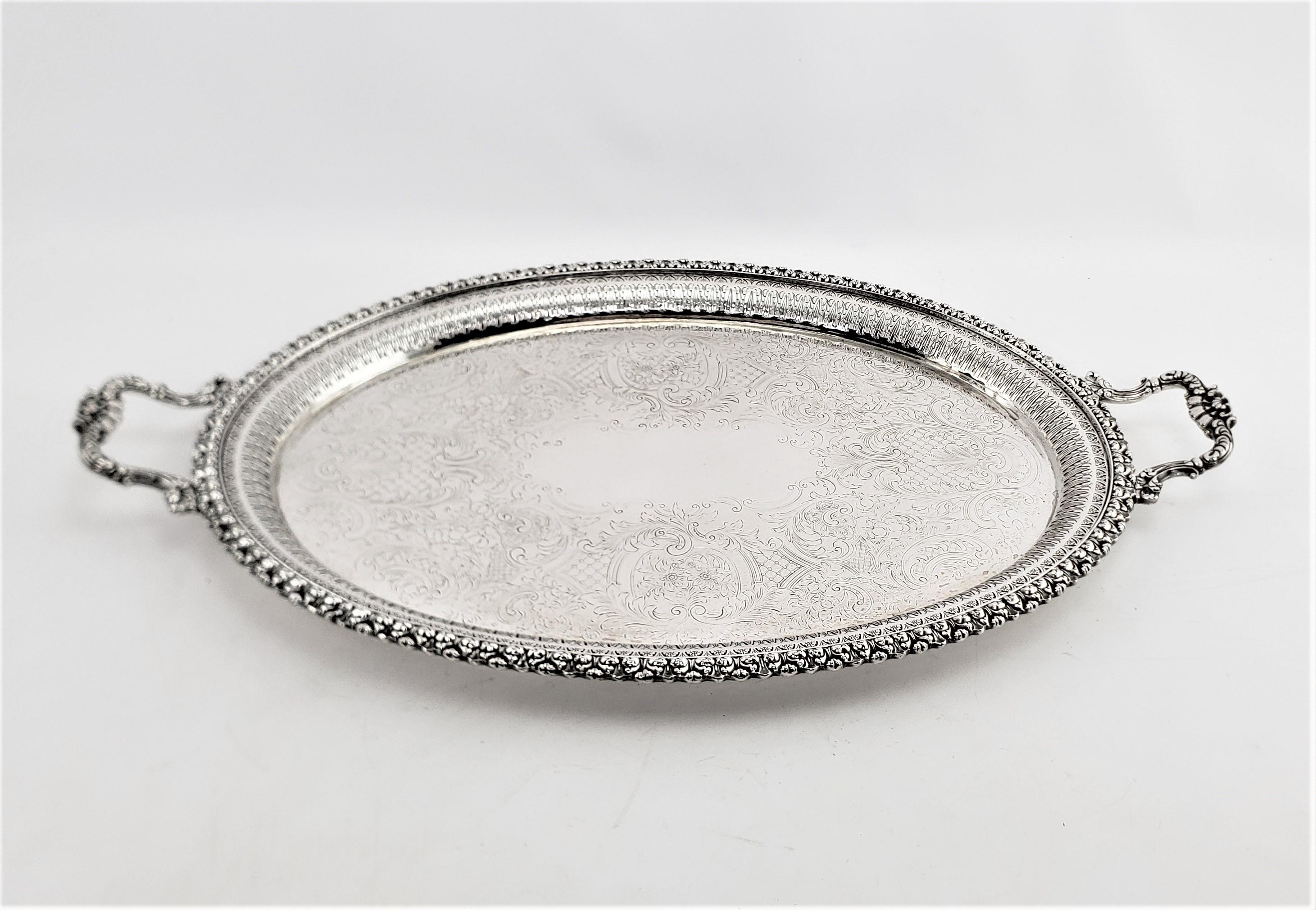 This antique silver plated serving tray was made by the renowned Barker-Ellis Silver Company of England, and dates to approximately 1920 and done in a Victorian style. This oval tray. The outer edge of the tray is done with an ornate stylized leaves