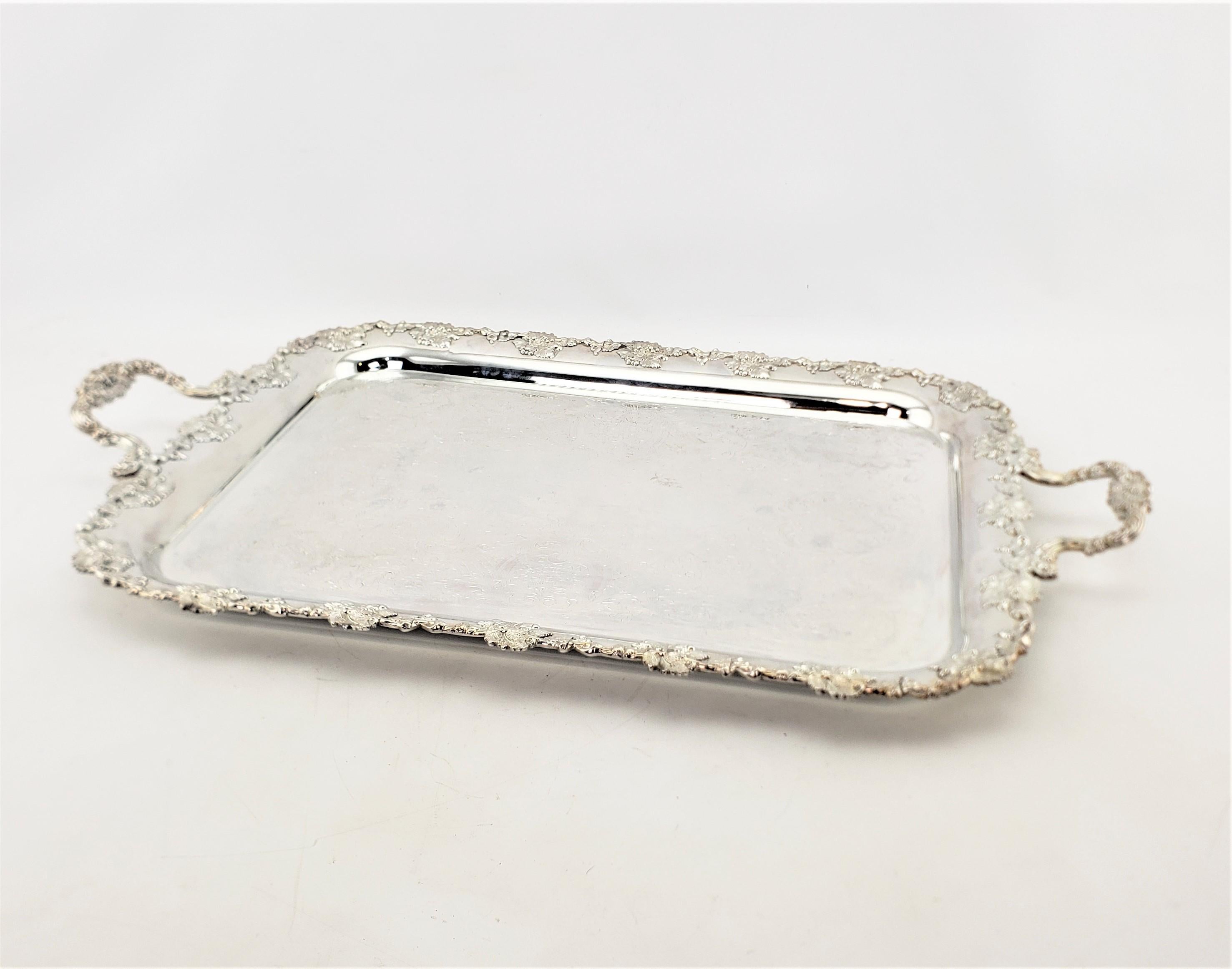 This large silver plated serving tray was made by the renowned Barker-Ellis Silver Co. of England in approximately 1890 in the period Victorian style. The tray is ornately decorated on the borders with applied leaves and berries, which is accented